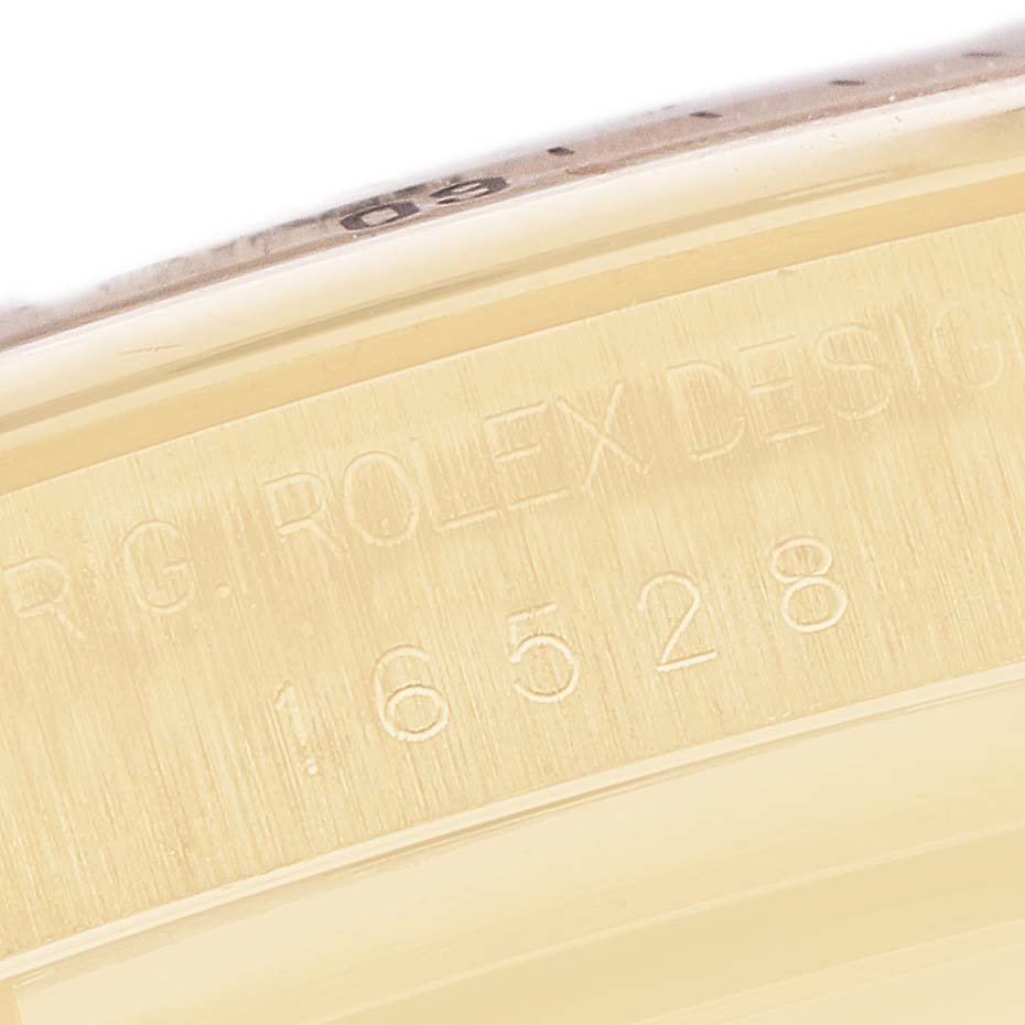The image shows a close-up of the side of a Rolex Daytona 16528 Men's Yellow Gold Champagne Dial watch, highlighting engraved numbers and text.