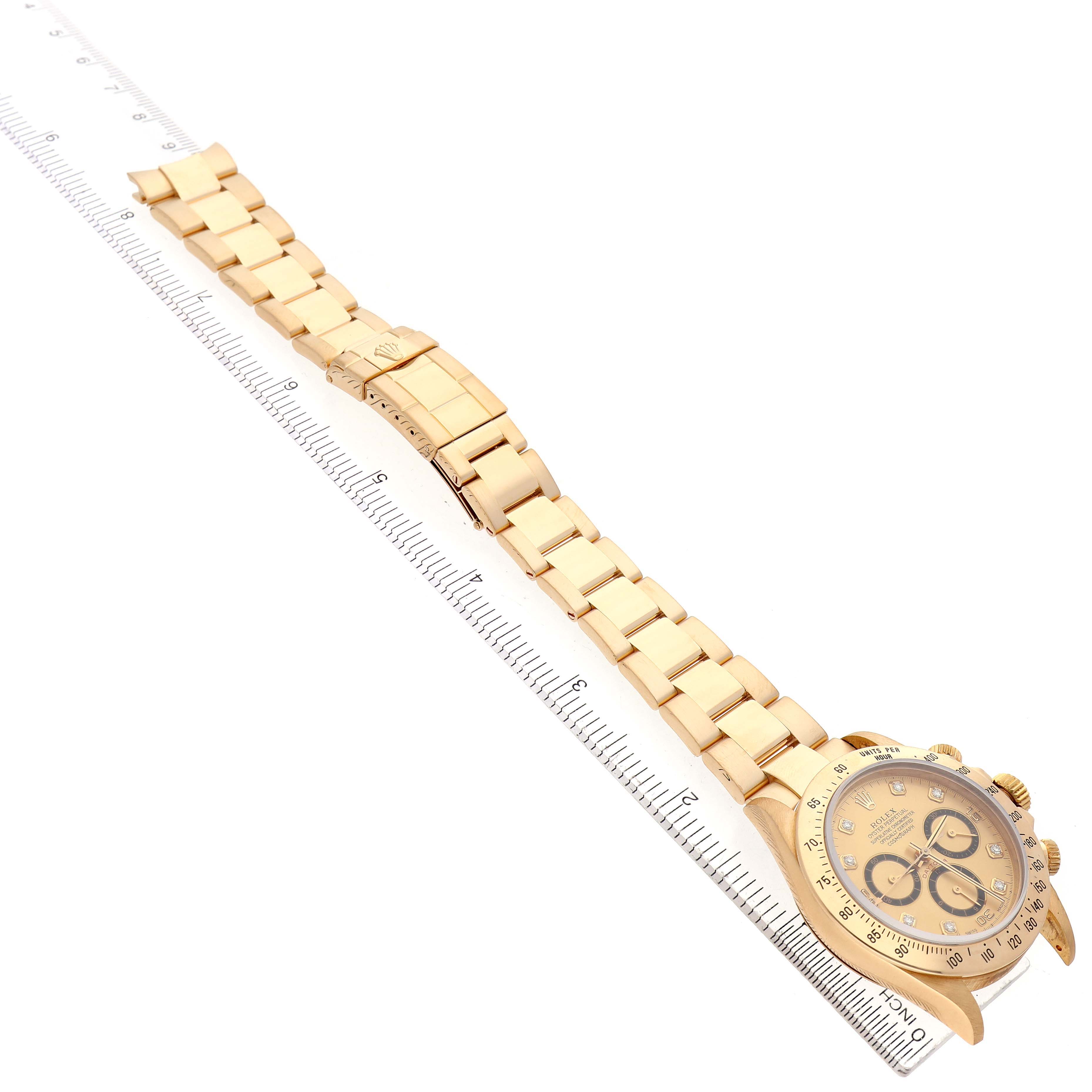 The Rolex Daytona 16528 Men's Yellow Gold Champagne Dial watch is shown from an angled, side view, highlighting its full bracelet and face alongside a ruler.