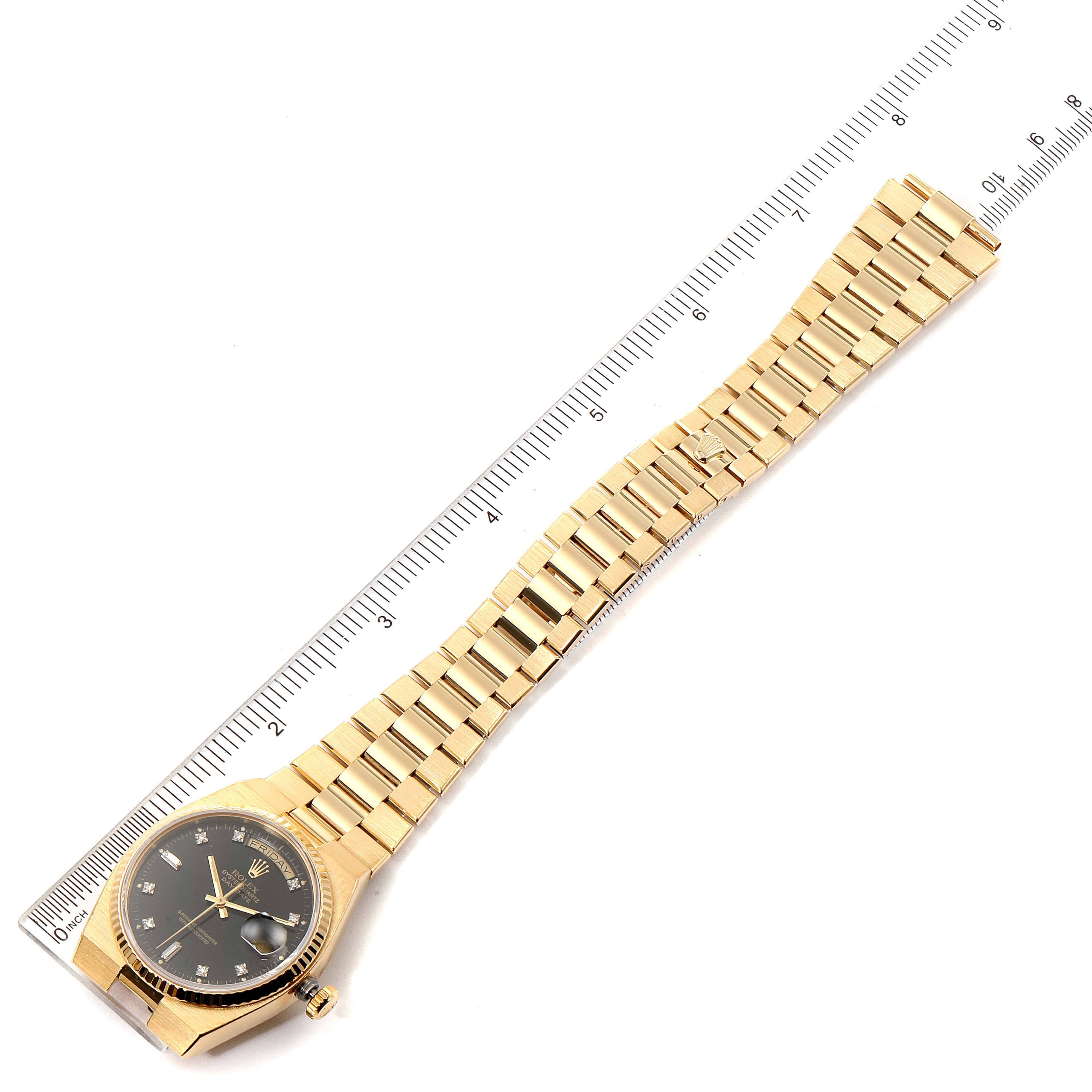 The image shows a Rolex President 19018 Men
s Yellow Gold Black Dial 19018 Men
s Yellow Gold Black Dial model watch laid flat with a ruler for scale, highlighting its bracelet and dial.