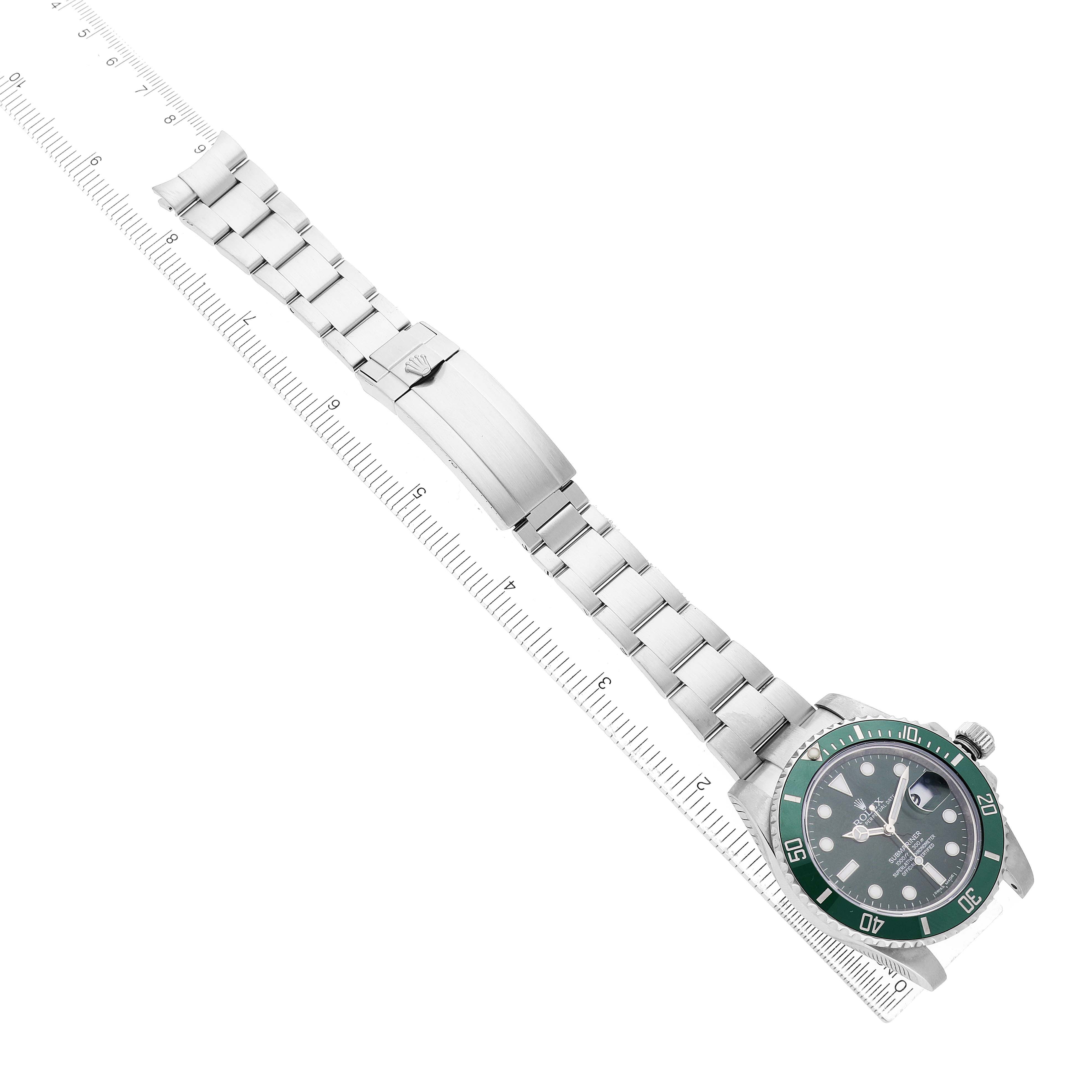 The Rolex Submariner 116610LV Men's Stainless Steel Green Dial watch is shown from a top view, displaying the face, bezel, bracelet, and clasp laid next to a ruler.