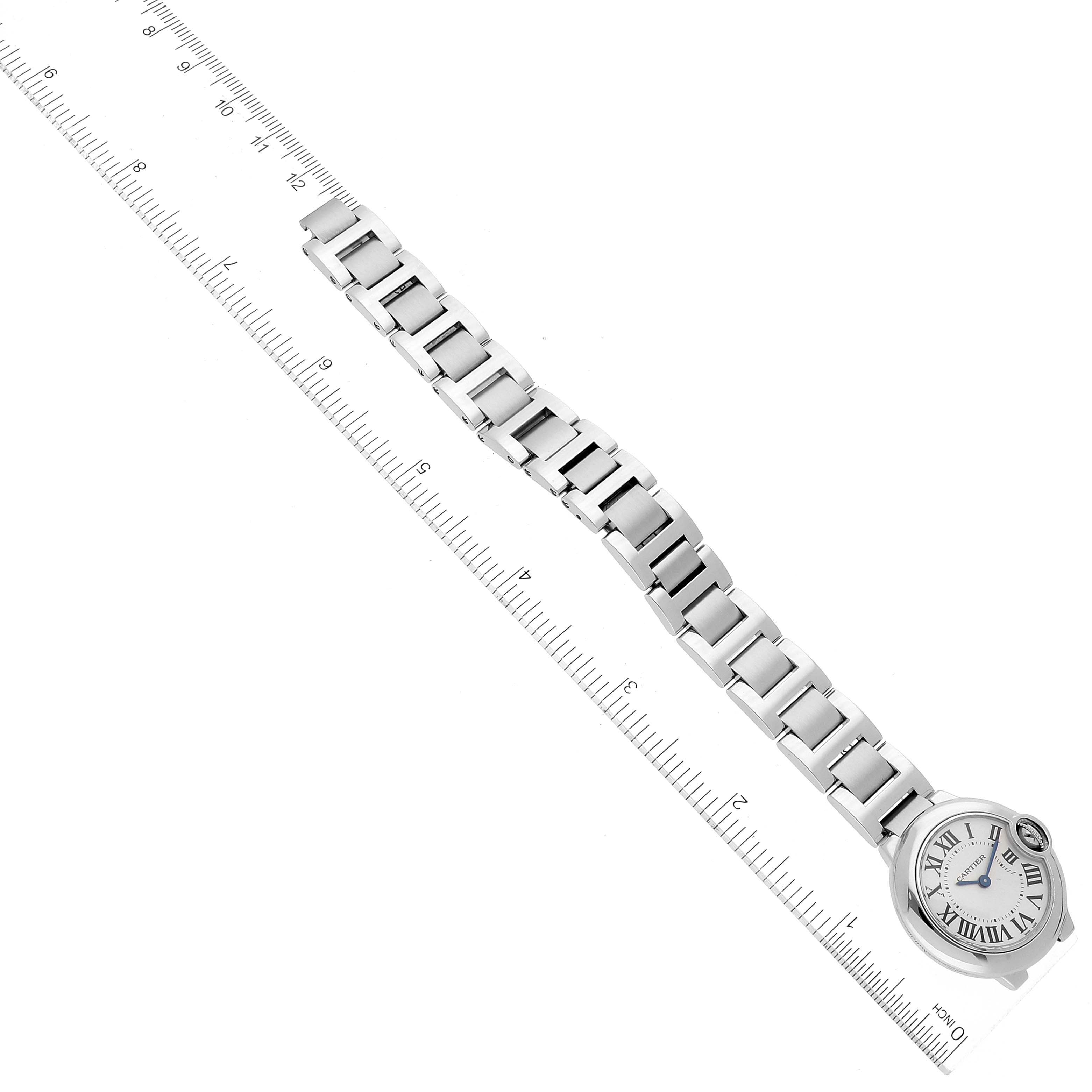 This image shows the Ballon Bleu watch by Cartier laid flat next to a ruler, displaying the watch face and the full length of the metal bracelet.