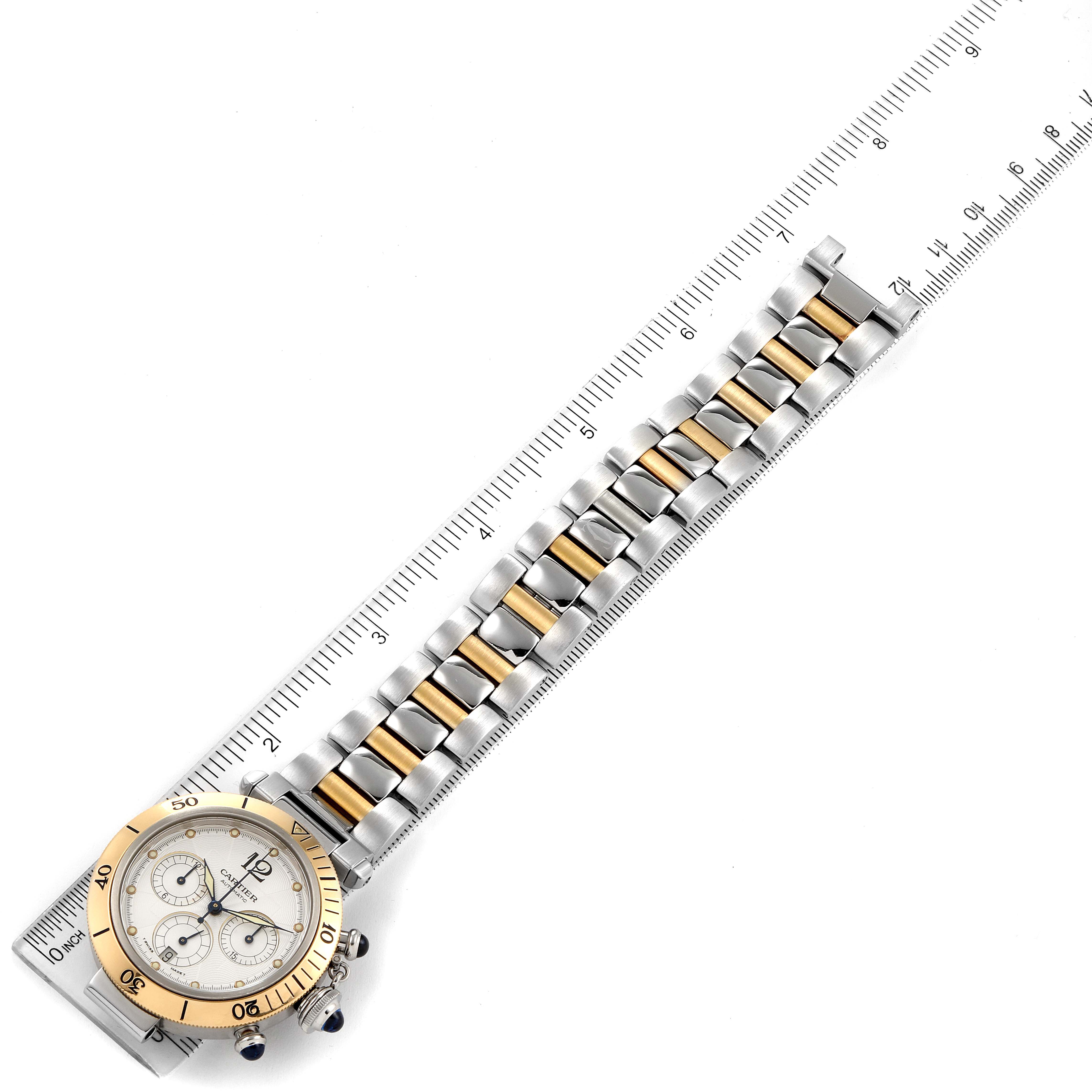 The image shows a Cartier Pasha W31036T6 Men's Steel and Gold (two tone) Silver Dial W31036T6 Men's Steel and Gold (two tone) Silver Dial watch with a stainless steel and gold bracelet, laid next to a ruler for measurement.