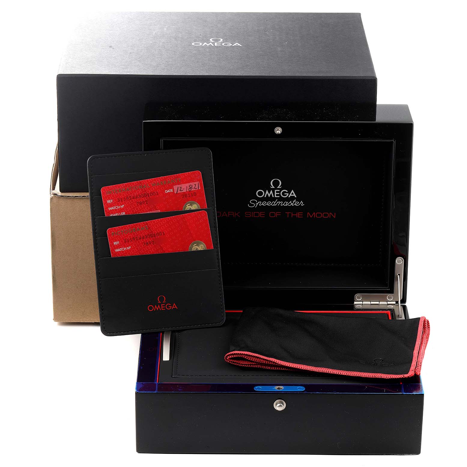 The image shows the packaging and accessories for an Omega Speedmaster 311.92.44.30.01.001 Men's Ceramic Black Dial 311.92.44.30.01.001 Men's Ceramic Black Dial watch, including cards, a cleaning cloth, and a storage box.