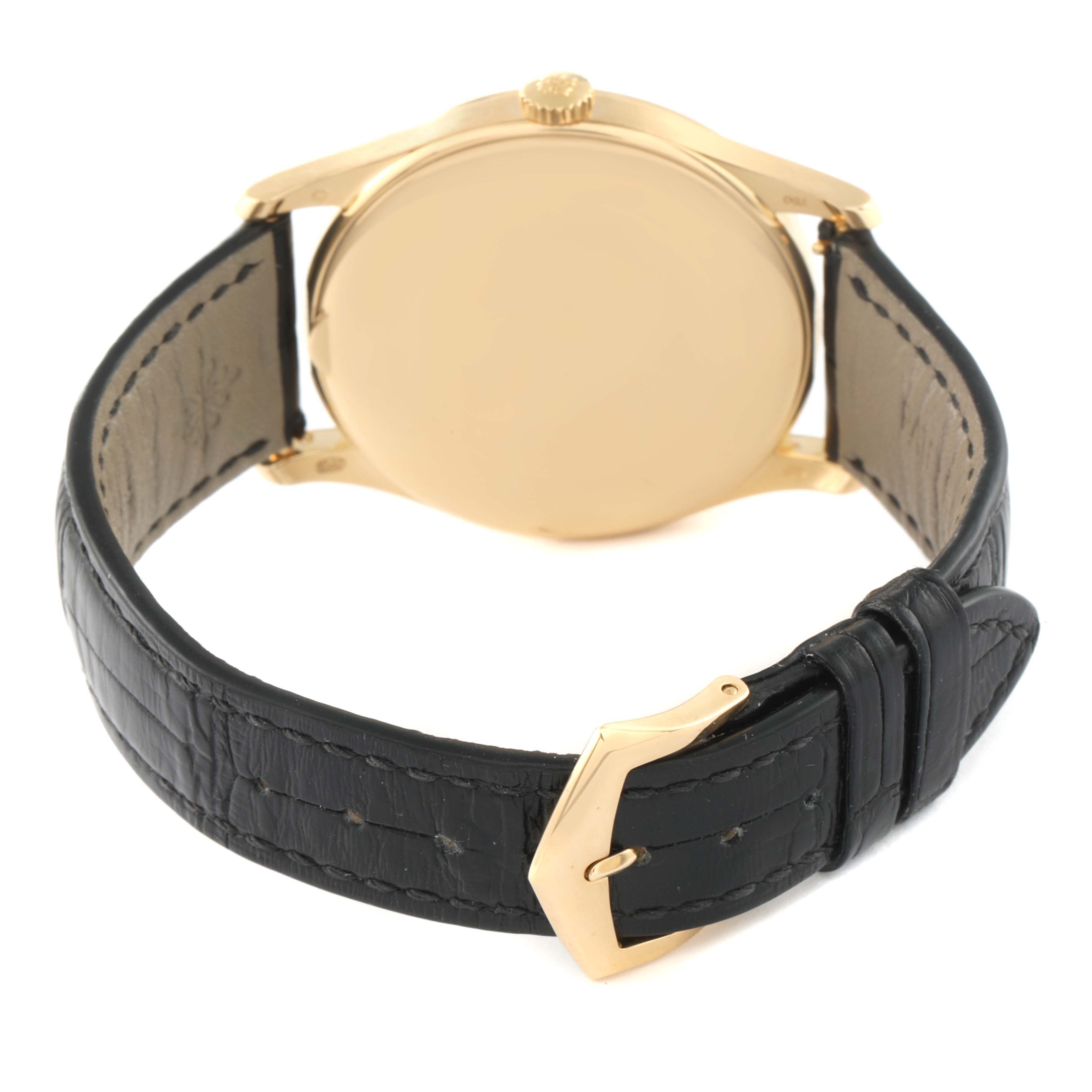 The image shows the back view of a Patek Philippe Calatrava 5196J Men's Yellow Gold Silver Dial 5196J Men's Yellow Gold Silver Dial watch, highlighting its gold case and black leather strap with a gold buckle.