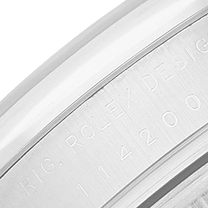 This image shows a close-up of the engraved edge of a Rolex Oyster Perpetual 114200 Men's Stainless Steel Silver Dial 114200 Men's Stainless Steel Silver Dial watch case with model and brand text visible.