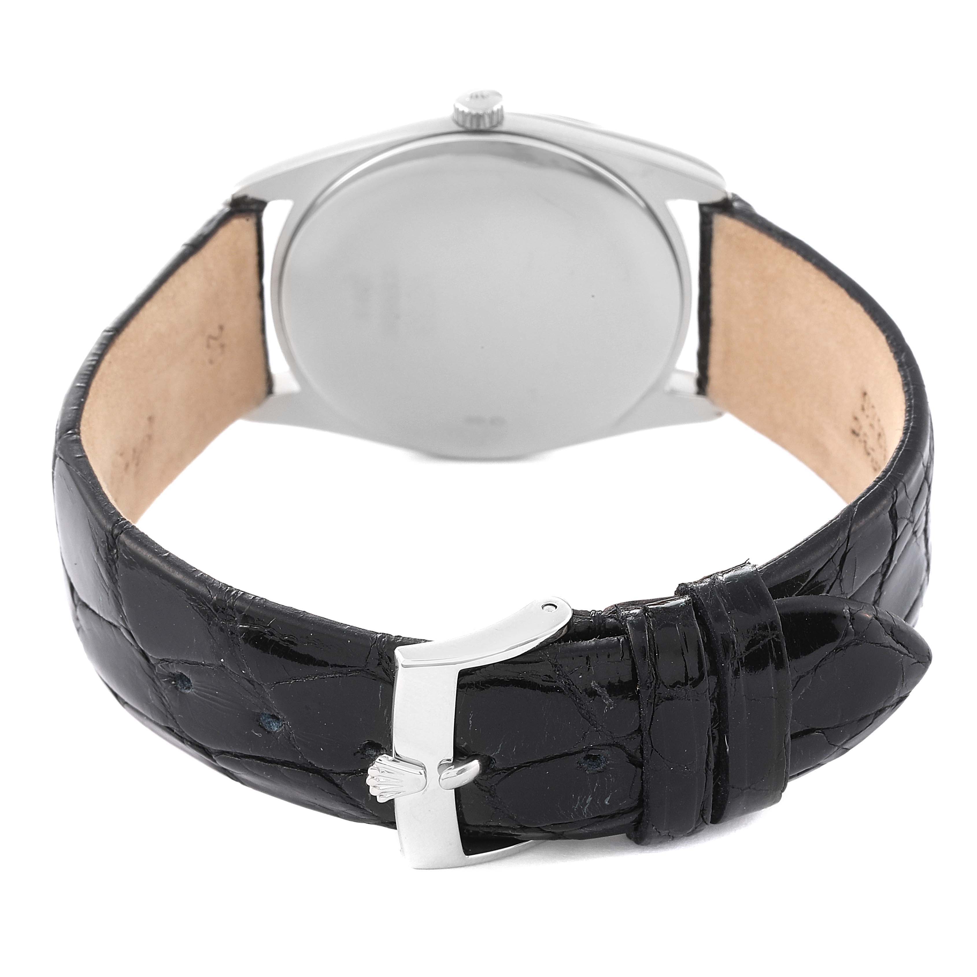 The image shows the back of a Rolex Cellini 4233 Men's White Gold Black Dial 4233 Men's White Gold Black Dial watch, displaying its black leather strap and clasp, and silver case.