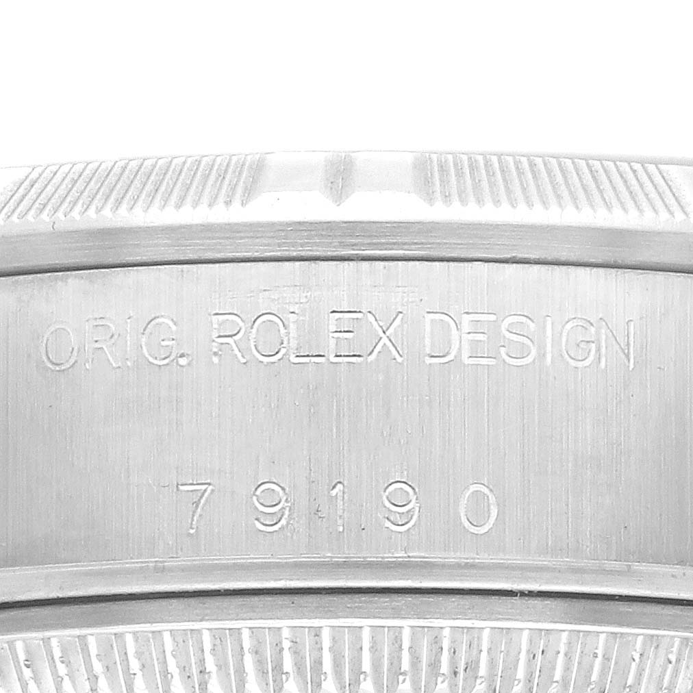 The image shows the engraved bezel or case edge of a Rolex Date 79190 Women
s Stainless Steel Silver Dial 79190 Women
s Stainless Steel Silver Dial model watch, focusing on its serial number and design inscription.