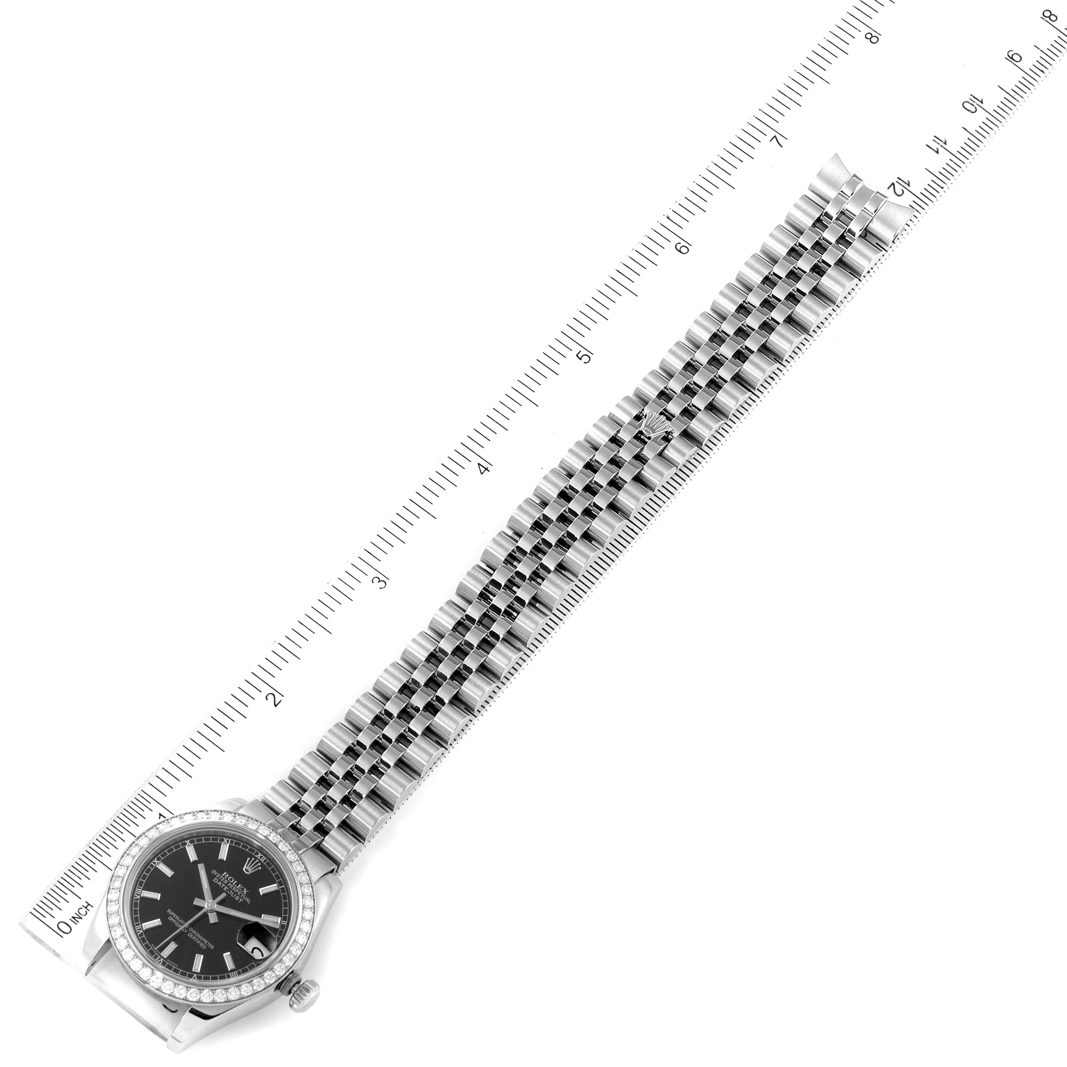 The image shows a top-down view of a Rolex Mid-Size 178384 Women's Stainless Steel Black Dial 178384 Women's Stainless Steel Black Dial watch with its bracelet aligned alongside a ruler.
