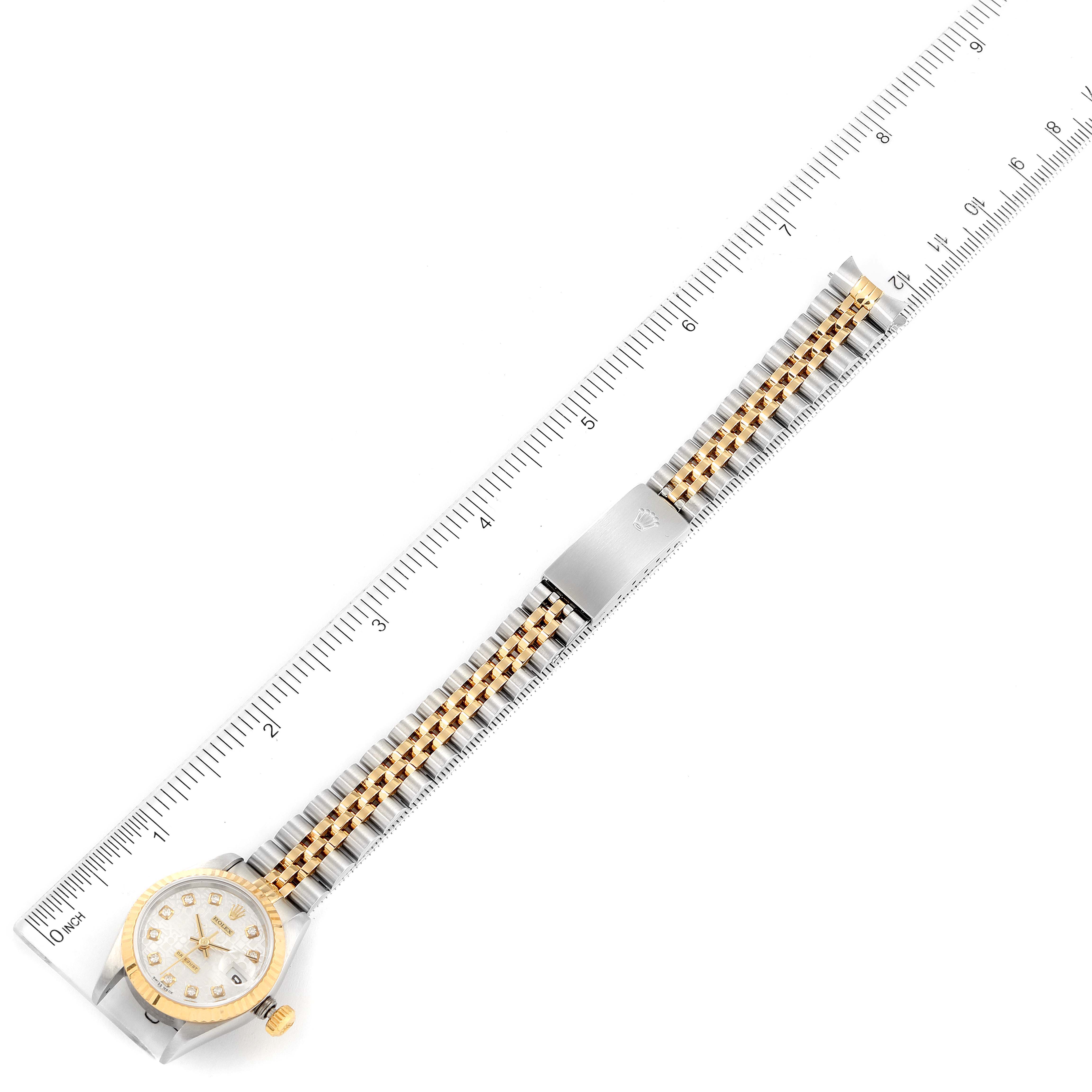 This image shows a top-down view of a Rolex Datejust 69173 Women
s Stainless Steel Silver Dial 69173 Women
s Stainless Steel Silver Dial watch, displaying its dial, bezel, and bicolor bracelet against a ruler for scale.