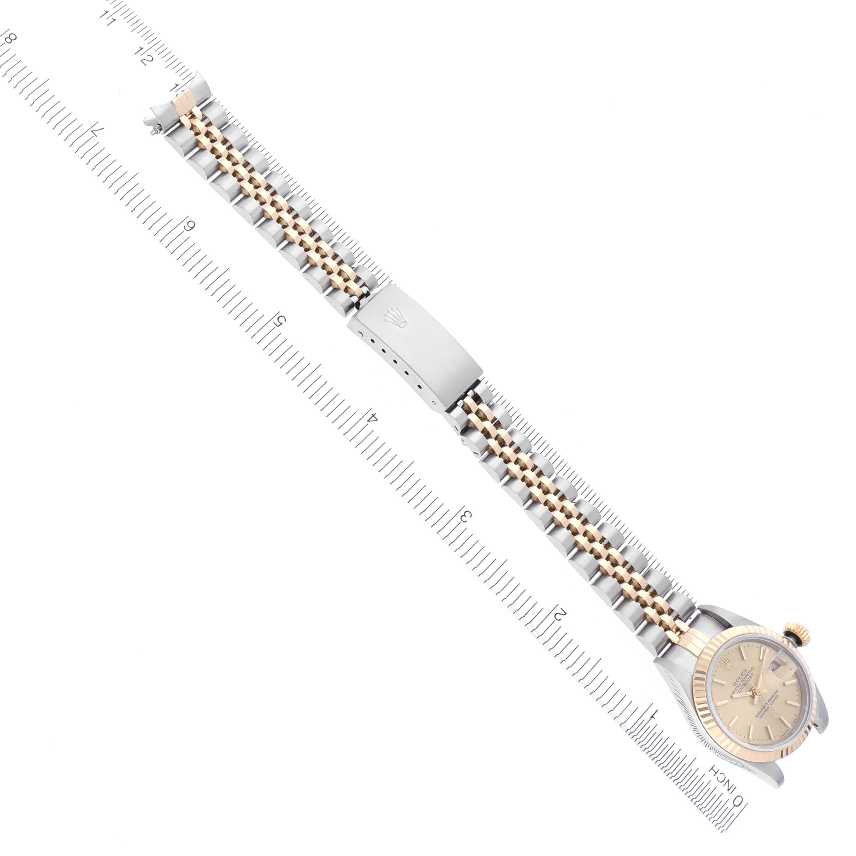 The Rolex Datejust 69173 Women's Steel and Gold (two tone) Champagne Dial 69173 Women's Steel and Gold (two tone) Champagne Dial watch is shown from a top view, displaying the bracelet, clasp, and watch face alongside a ruler for scale.