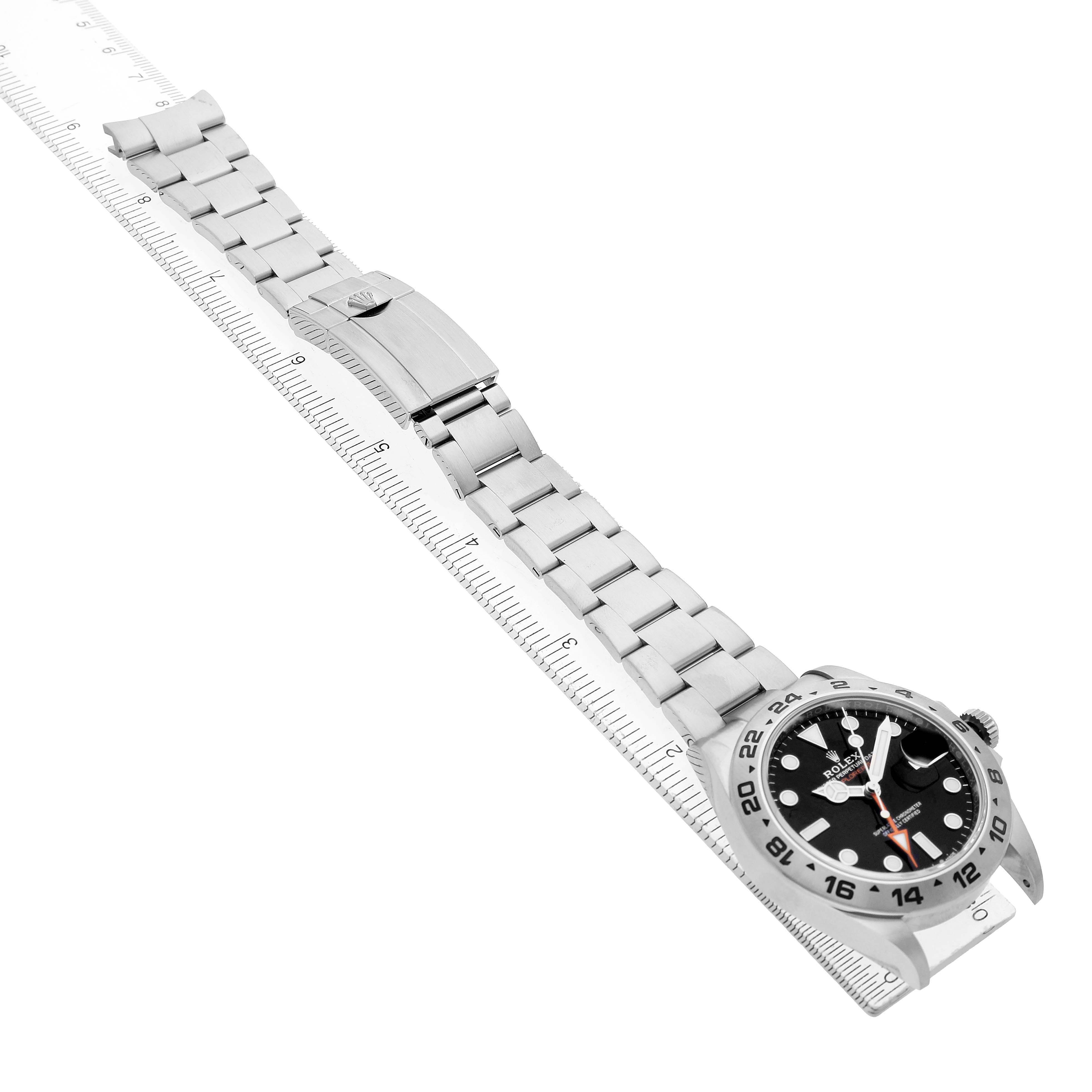 The Rolex Explorer 226570 Men's Stainless Steel Black Dial watch is shown at an angle displaying the face, bezel, and bracelet alongside a measuring ruler.
