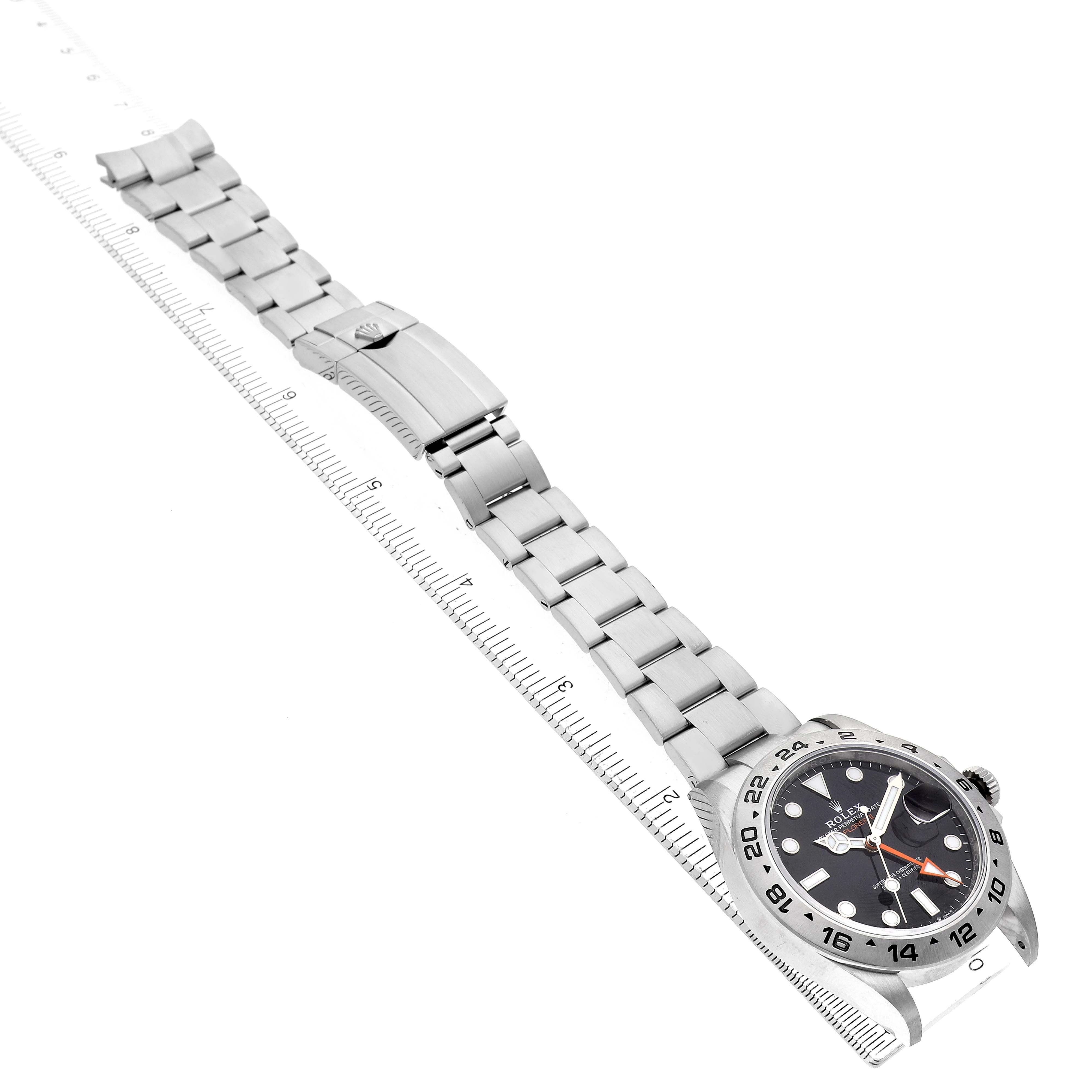 The Rolex Explorer 226570 Men's Stainless Steel Black Dial watch is shown at a top-down angle, displaying the full bracelet alongside a ruler for scale.
