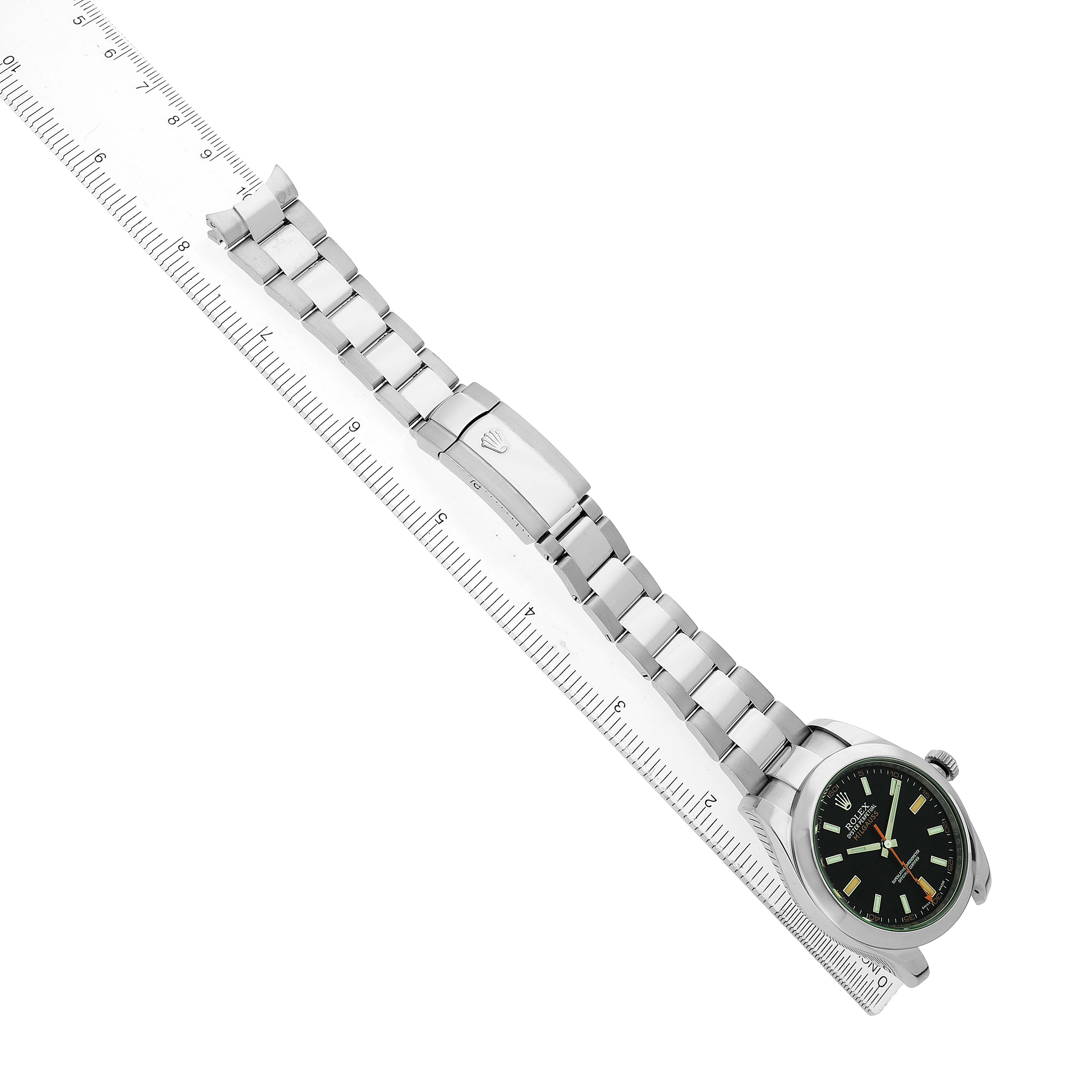 The Rolex Milgauss 116400GV Men's Stainless Steel Black Dial watch is shown at an angled side view, highlighting the face, bracelet, and clasp next to a ruler.