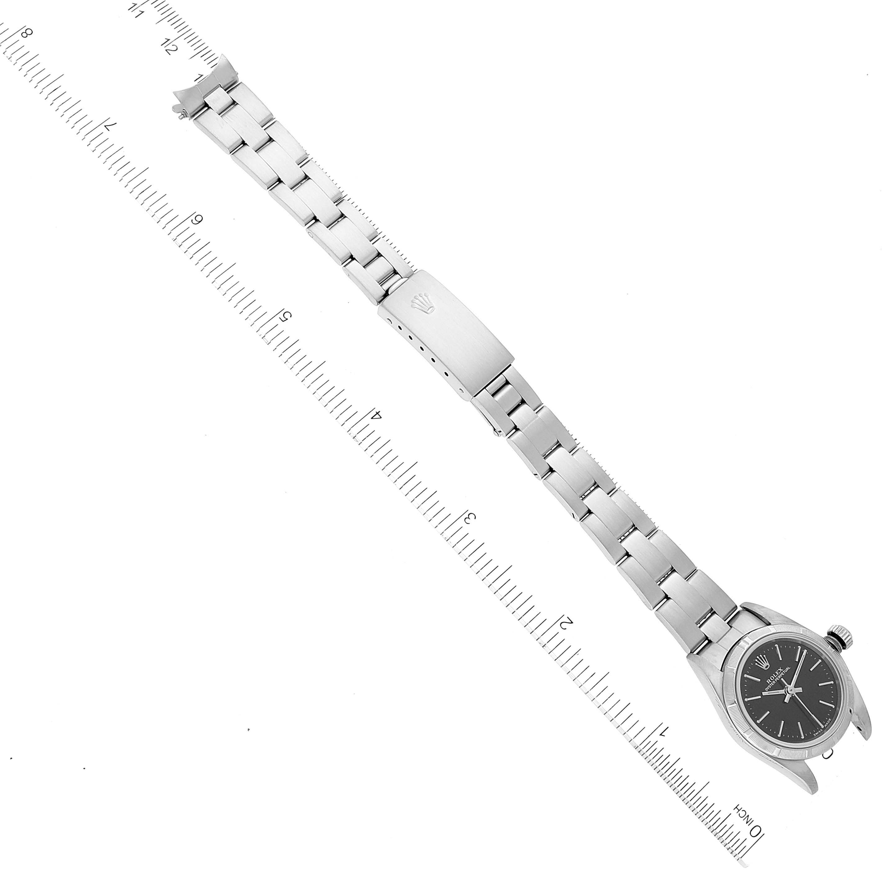 The image shows a Rolex Oyster Perpetual 76030 Women's Stainless Steel Black Dial 76030 Women's Stainless Steel Black Dial watch laid flat with its bracelet fully extended and a ruler in the background.