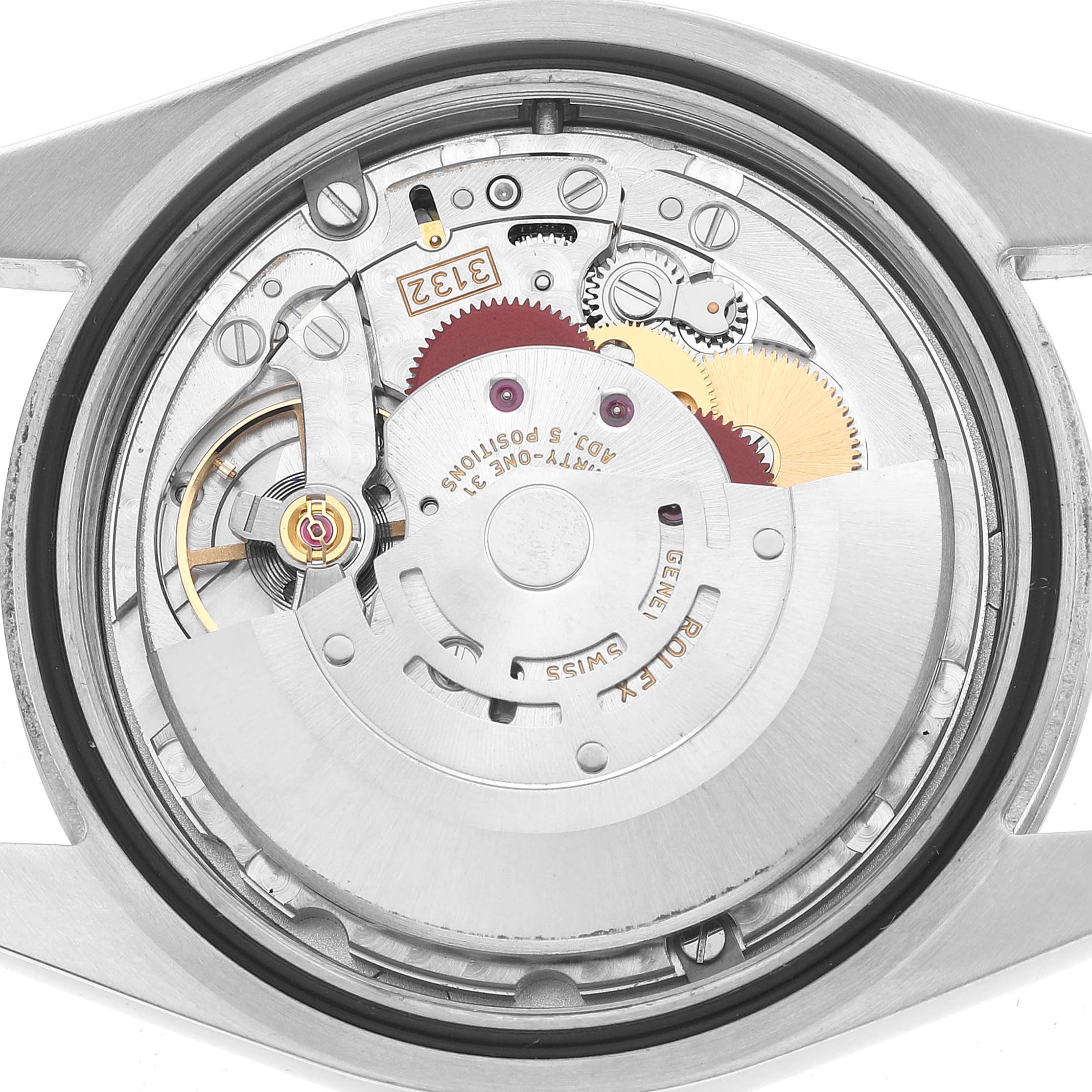 The image shows a top view of the movement inside a Rolex Oyster Perpetual 114300 Men's Stainless Steel Blue Dial, highlighting gears and mechanical components.