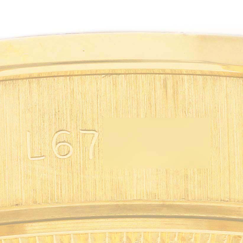 The image shows a close-up of the edge and serial number of a Rolex President 69138 Women's Yellow Gold Champagne Dial 69138 Women's Yellow Gold Champagne Dial watch, focusing on its gold casing.