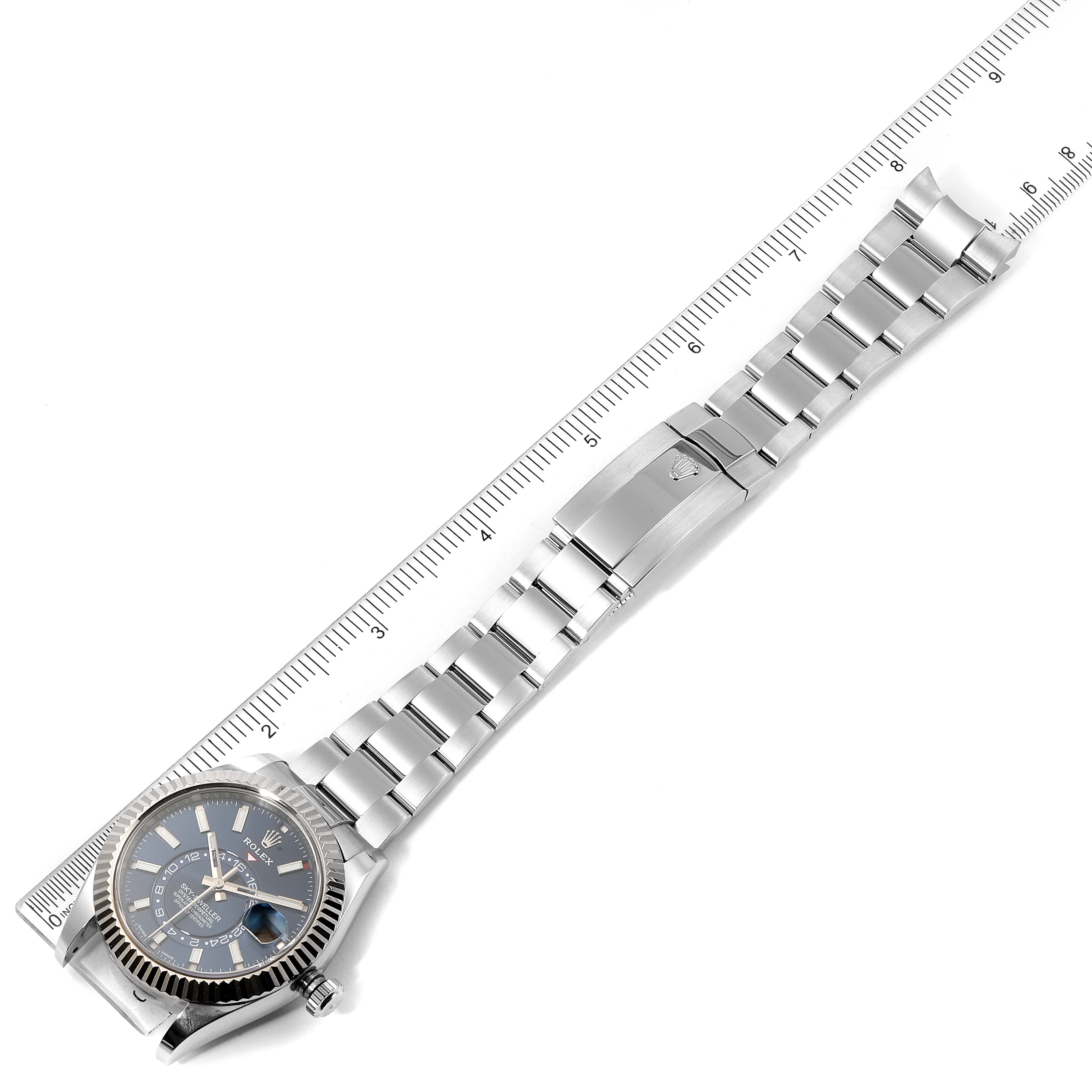 The image shows a top view of a Rolex Sky-Dweller 326934 Men's Stainless Steel Blue Dial 326934 Men's Stainless Steel Blue Dial with its watch face, bracelet, and clasp displayed against a ruler.