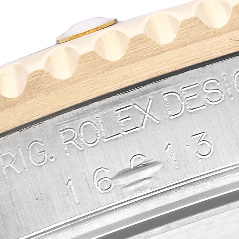 The image shows a close-up of the Rolex Submariner 16613 Men's Steel and Gold (two tone) Black Dial 16613 Men's Steel and Gold (two tone) Black Dial model's engraved bezel and case side.