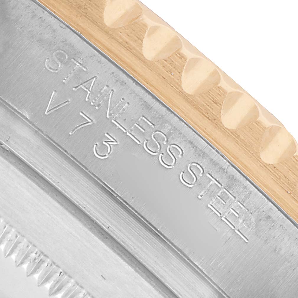 The image shows a close-up of the engraved edge and bezel of a Rolex Submariner 116613 Men's Steel and Gold (two tone) Blue Dial, highlighting the stainless steel material.