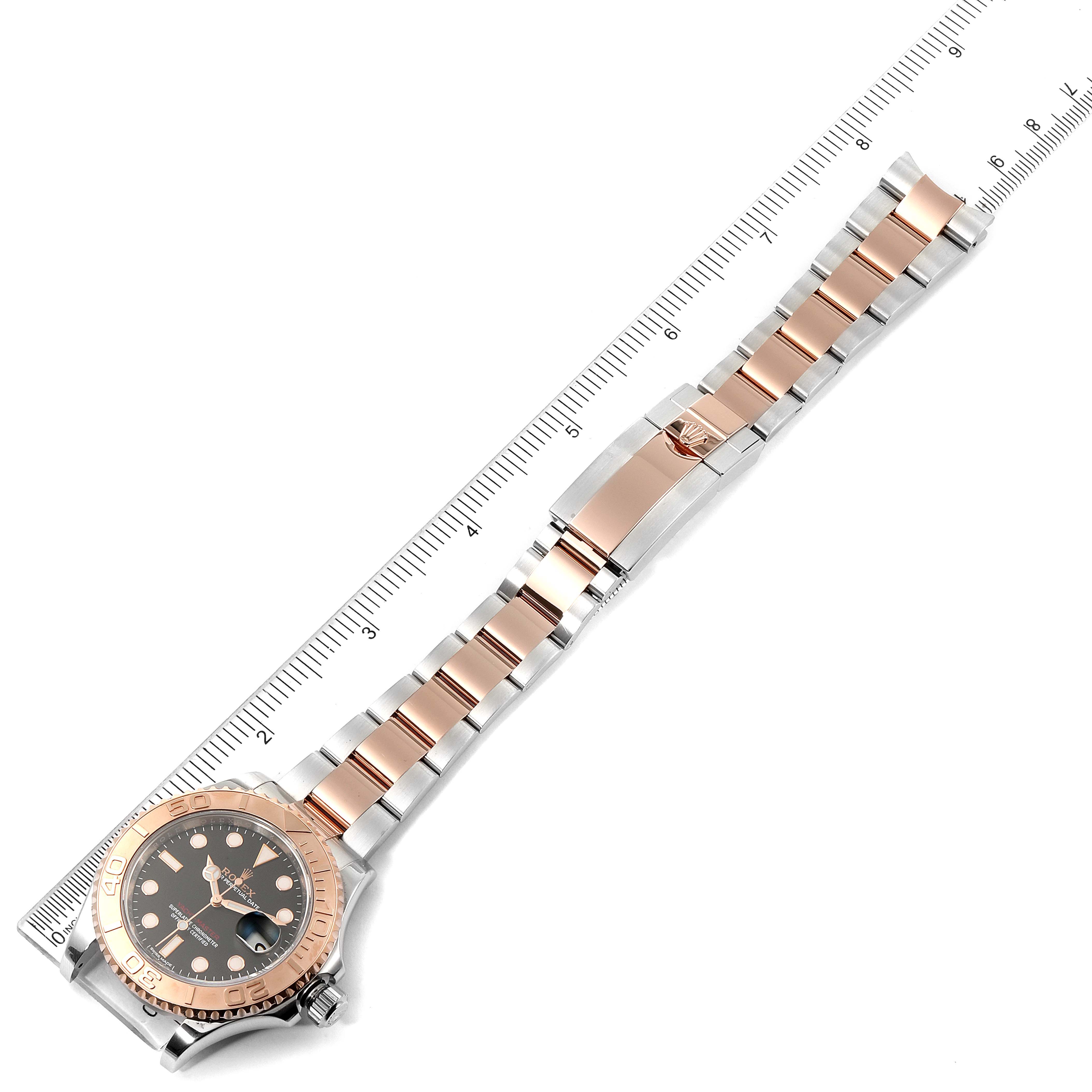 The Rolex Yacht-Master 116621 Men
s Steel and Gold (two tone) Black Dial 116621 Men
s Steel and Gold (two tone) Black Dial watch is shown from a top-down angle, displaying its face, bezel, and bracelet next to a measuring scale.