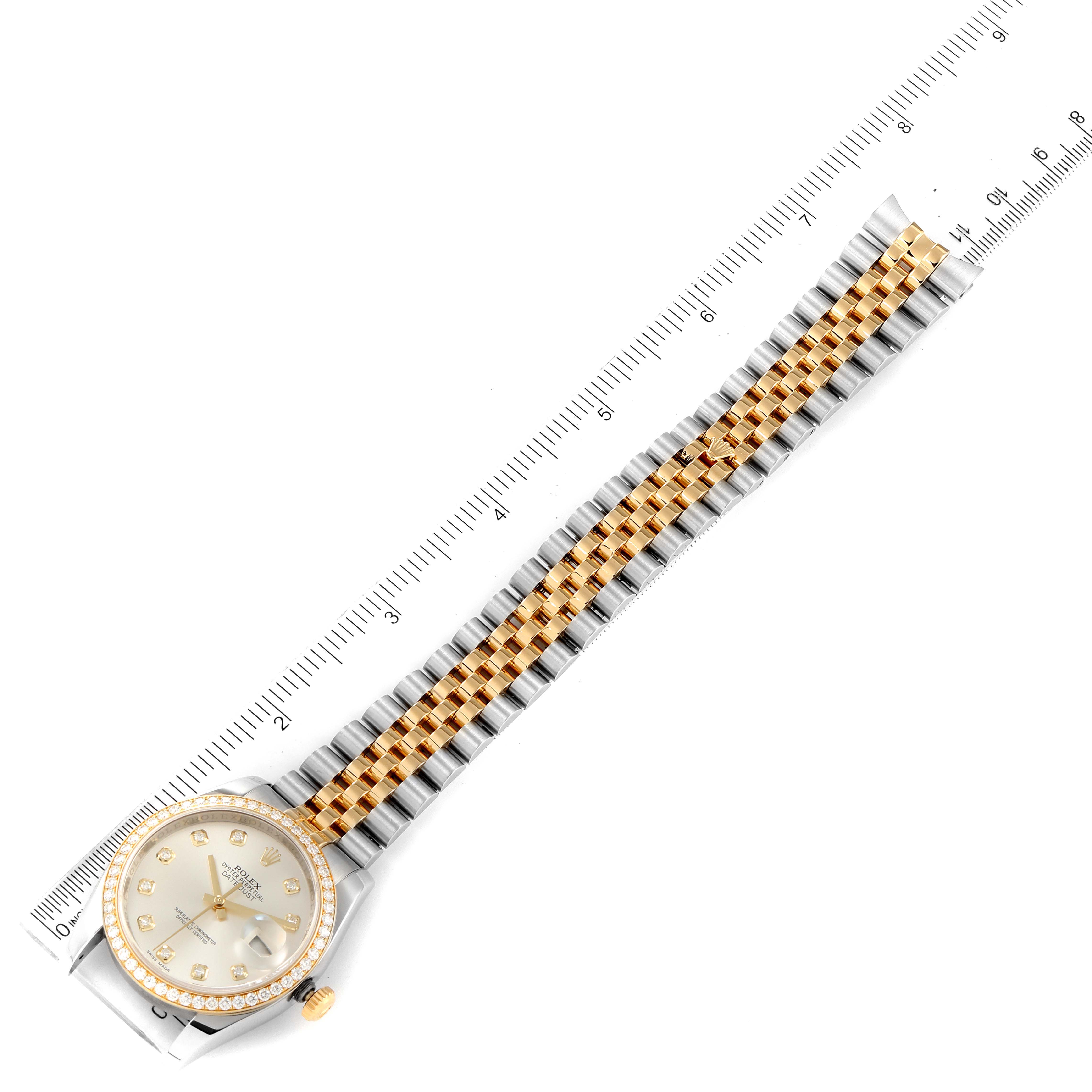 The image shows a top-down view of a Rolex Datejust 116243 Men's Steel and Gold (two tone) Silver Dial 116243 Men's Steel and Gold (two tone) Silver Dial watch, including the watch face, bezel, and bracelet against a ruler.