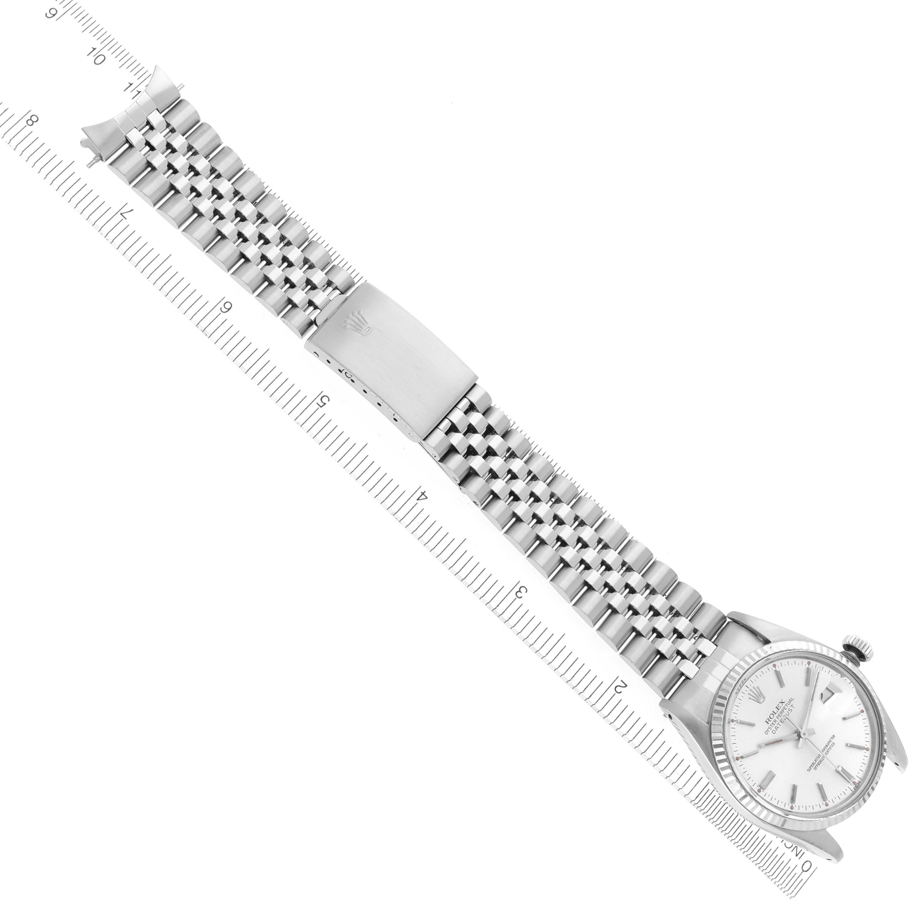 The Rolex Datejust 16014 Men's Stainless Steel Silver Dial 16014 Men's Stainless Steel Silver Dial watch is shown from a top view with its full bracelet and clasp extended, alongside a ruler for scale.