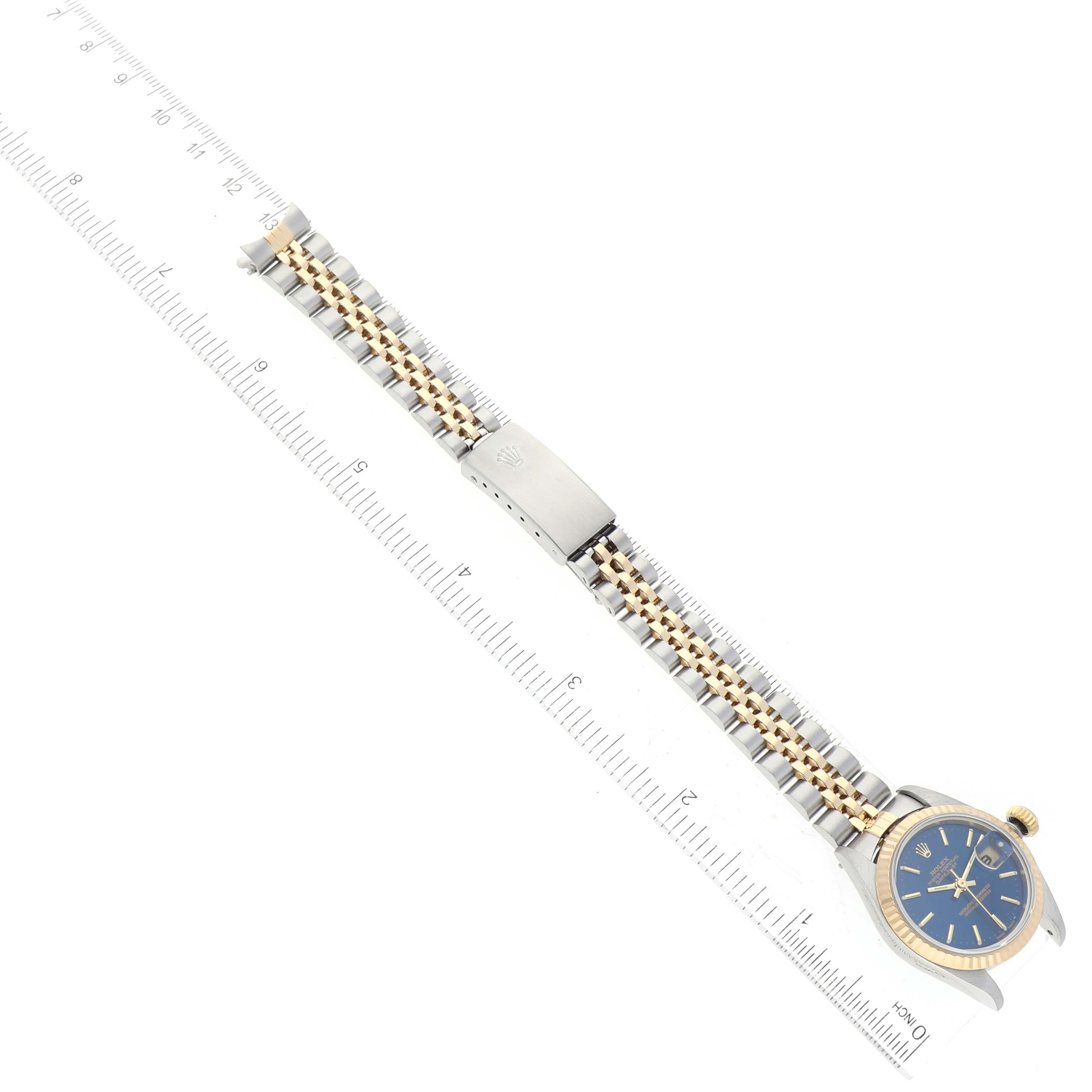 The Rolex Datejust 79173 Women's Steel and Gold (two tone) Blue Dial 79173 Women's Steel and Gold (two tone) Blue Dial watch is shown from an overhead angle, displaying the dial, bezel, and Jubilee bracelet alongside a ruler for scale.