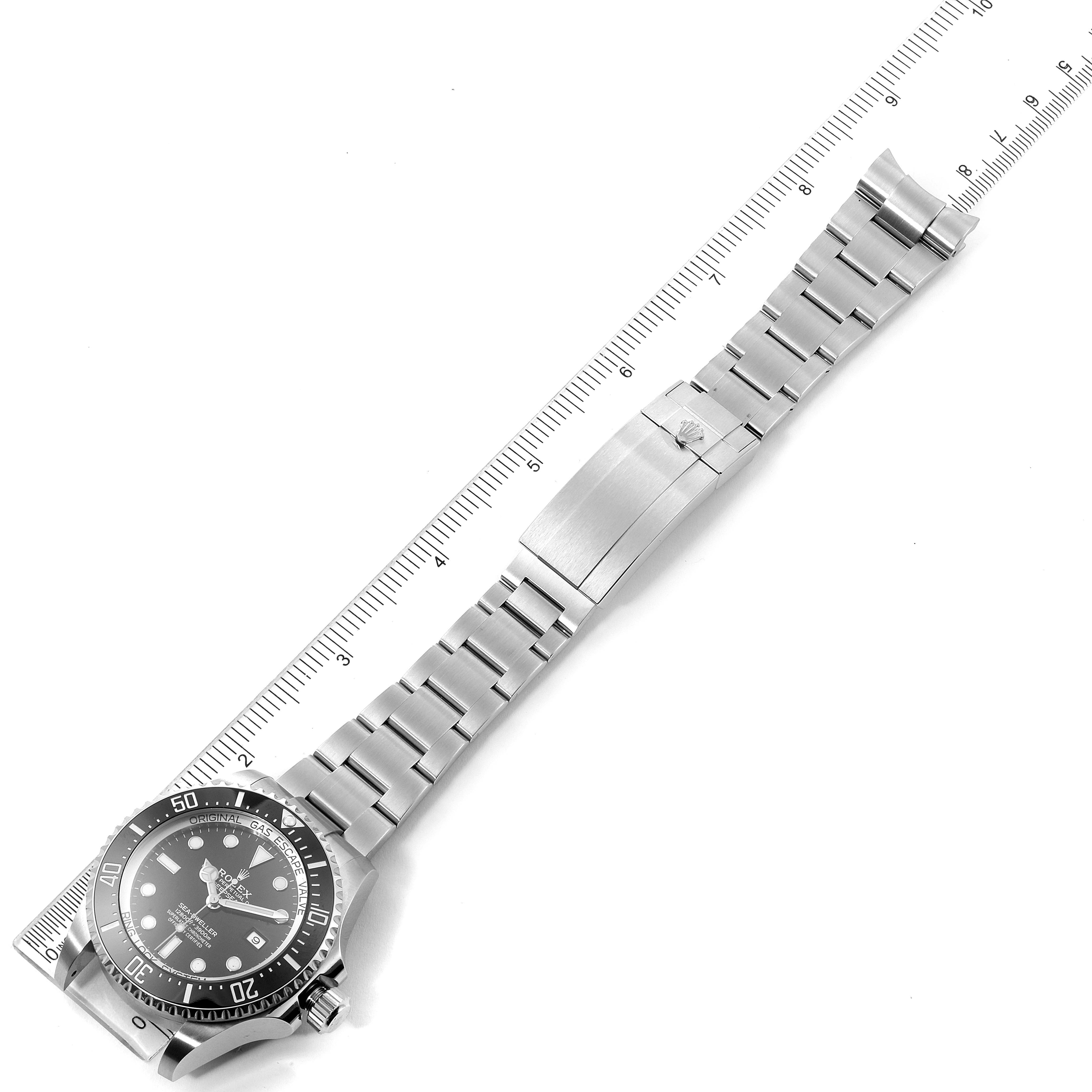 The image shows a Rolex Sea-Dweller 126660 Men
s Stainless Steel Black Dial 126660 Men
s Stainless Steel Black Dial watch laid flat with a measurement scale, displaying the face, bezel, and metal bracelet.