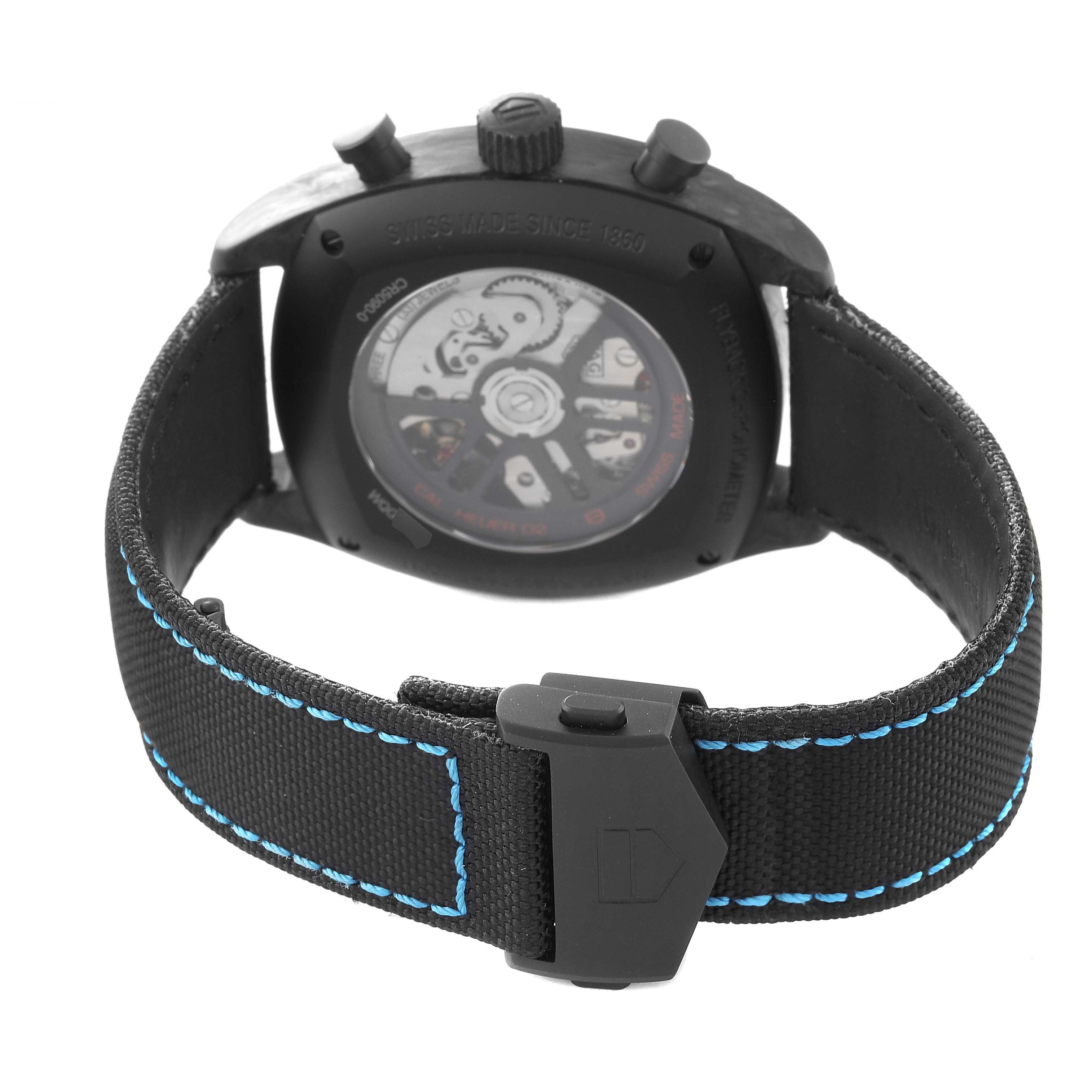 The image shows the back of a Tag Heuer Monza CR5090.FN6001 Men's Titanium Grey Dial watch, highlighting its transparent case back and strap with blue stitching.