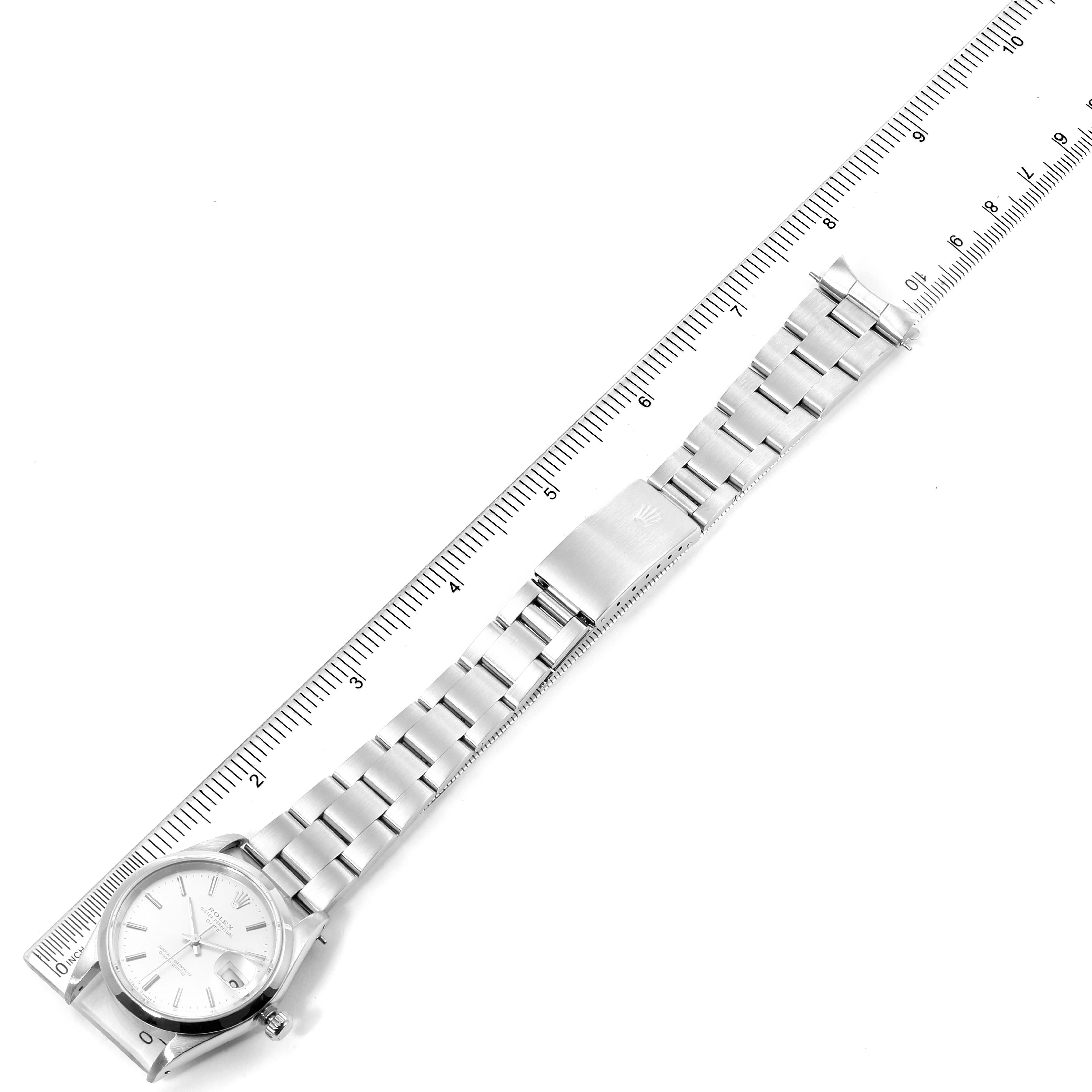 The image shows a top-down view of a Rolex Date 15200 Men's Stainless Steel Silver Dial 15200 Men's Stainless Steel Silver Dial model watch laid flat against a ruler, highlighting the bezel, dial, bracelet, and clasp.