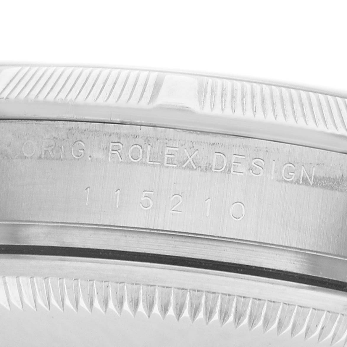 The image shows a close-up of the side of a Rolex Date 115210 Men's Stainless Steel Black Dial watch, highlighting its engraved bezel and model number.