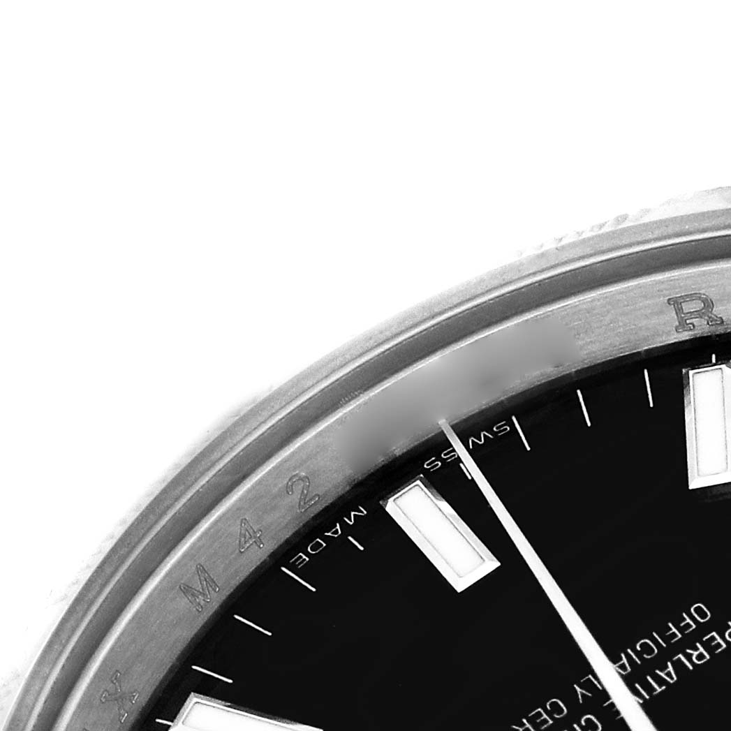 The image shows a close-up of a Rolex Date 115210 Men's Stainless Steel Black Dial model watch, highlighting the bezel and part of the dial with hour markers.