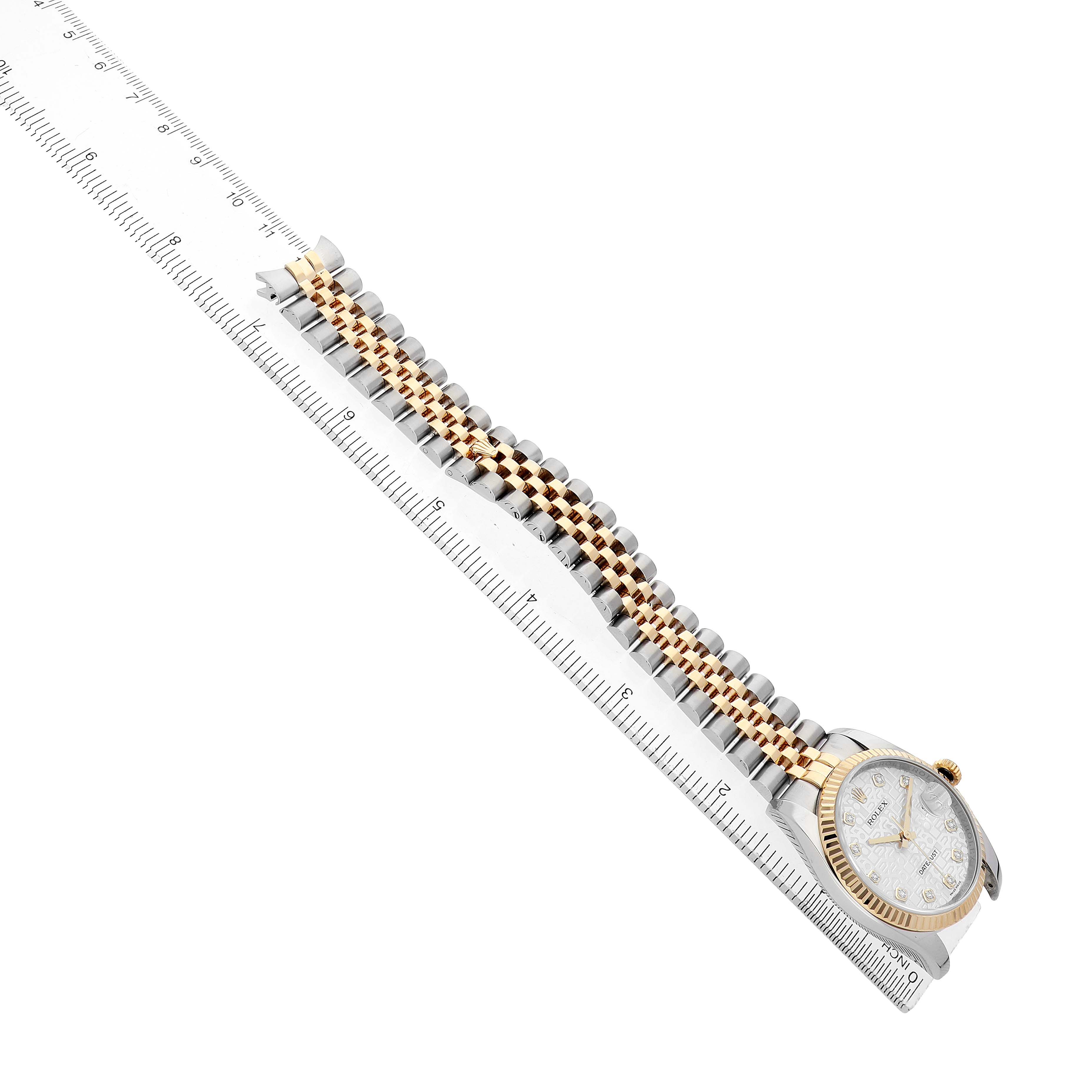 The Rolex Datejust 116233 Men's Steel and Gold (two tone) Silver Dial watch is shown at a diagonal angle, displaying the bracelet and watch face alongside a ruler.