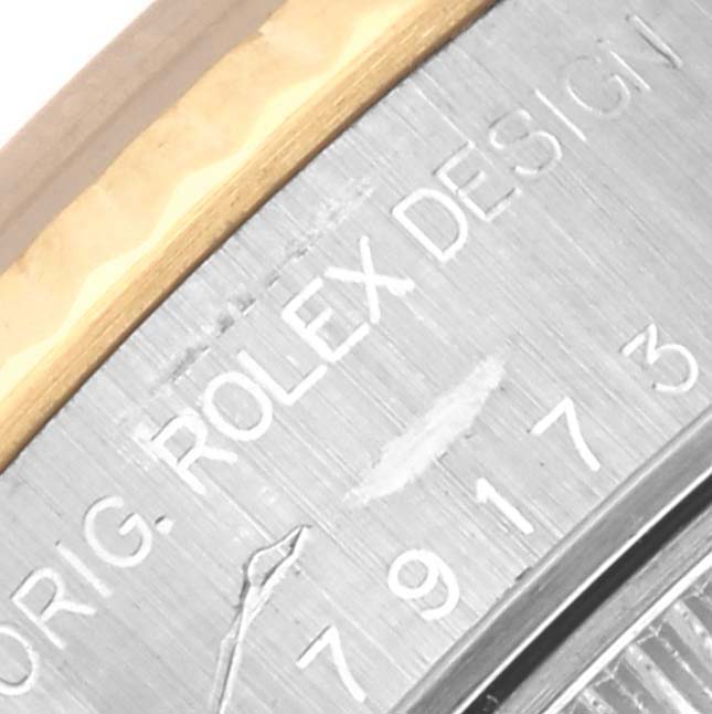 This image shows the edge of the case back and part of the watch band on a Rolex Datejust 79173 Women's Steel and Gold (two tone) Blue Dial 79173 Women's Steel and Gold (two tone) Blue Dial, focusing on the engravings.