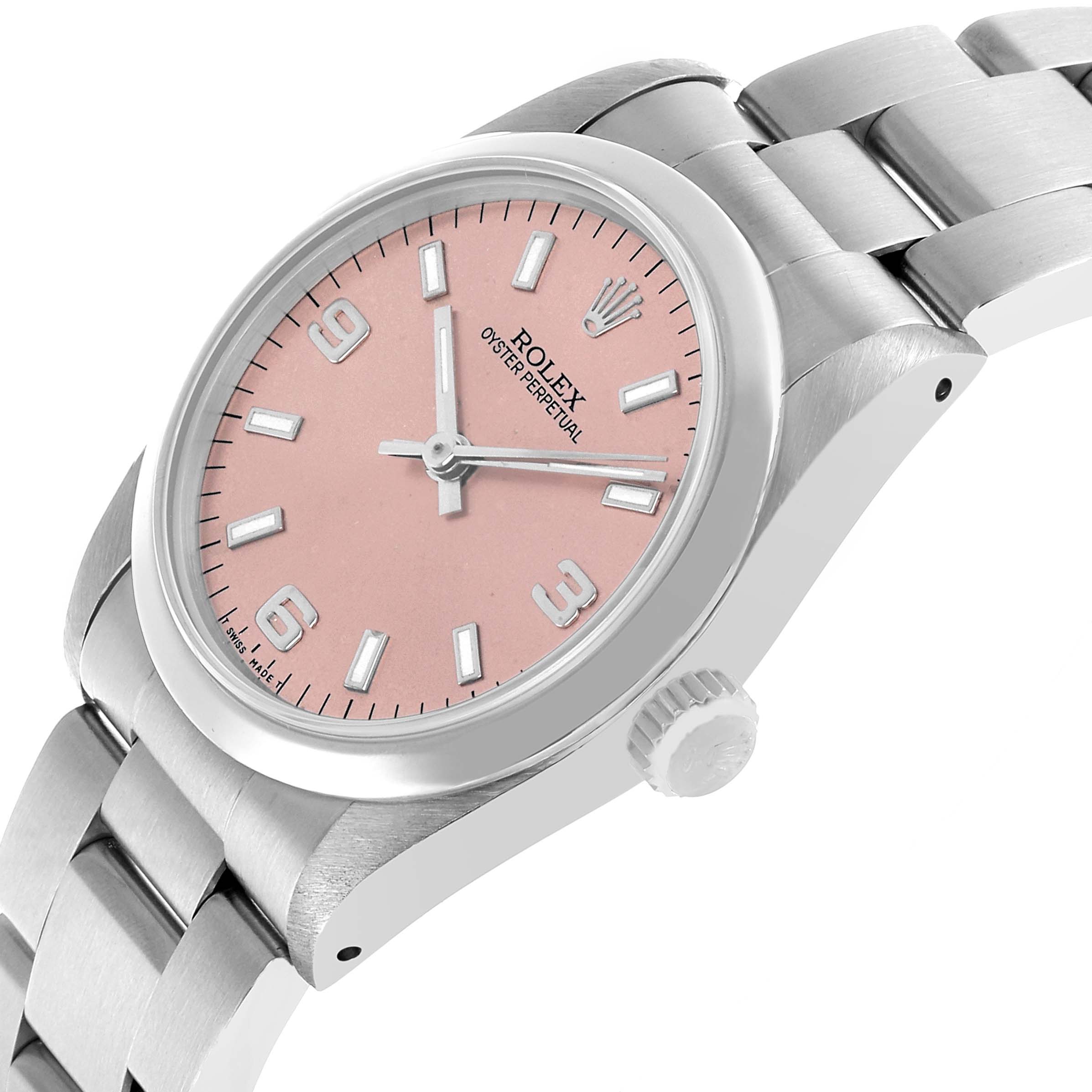 The Rolex Oyster Perpetual 67480 Women's Stainless Steel Pink Dial watch is shown at a slight angle, highlighting the pink dial, case, crown, and part of the bracelet.