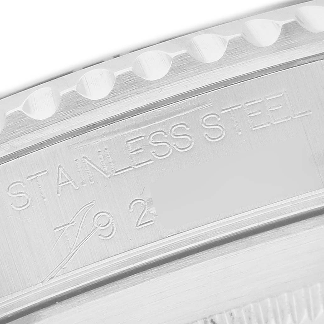 The image shows a macro view of the case side of a Rolex Submariner 14060 Men's Stainless Steel Black Dial, highlighting "STAINLESS STEEL" engraving.