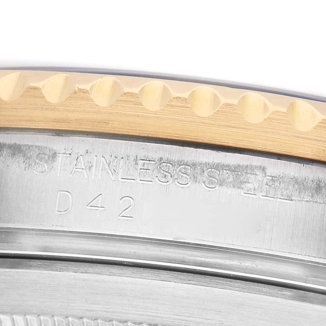 The image shows a close-up of the Submariner model by Rolex, focusing on the engraved stainless steel case and the edge of the bezel.