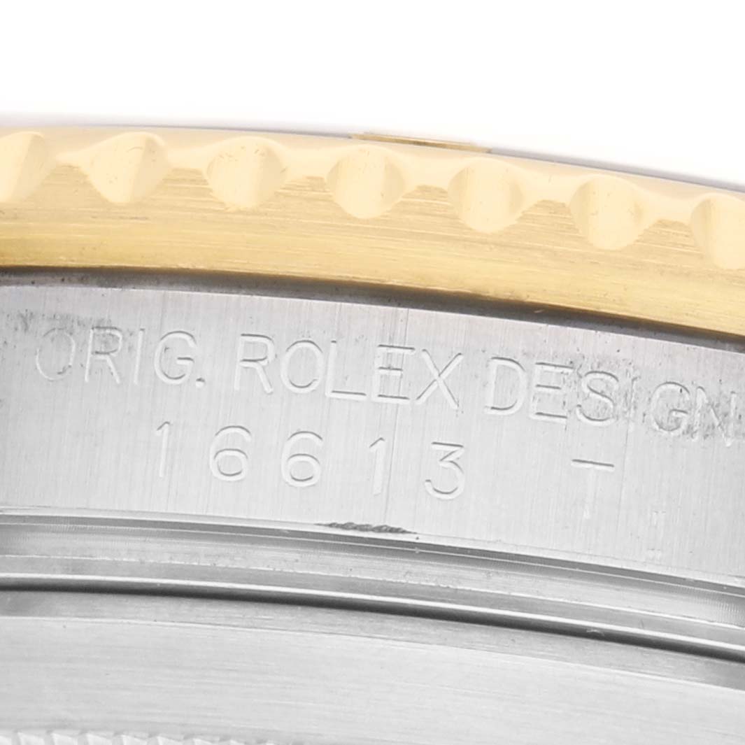 The image shows a close-up of the case edge of a Rolex Submariner 16613 Men's Steel and Gold (two tone) Black Dial, displaying engraving details.