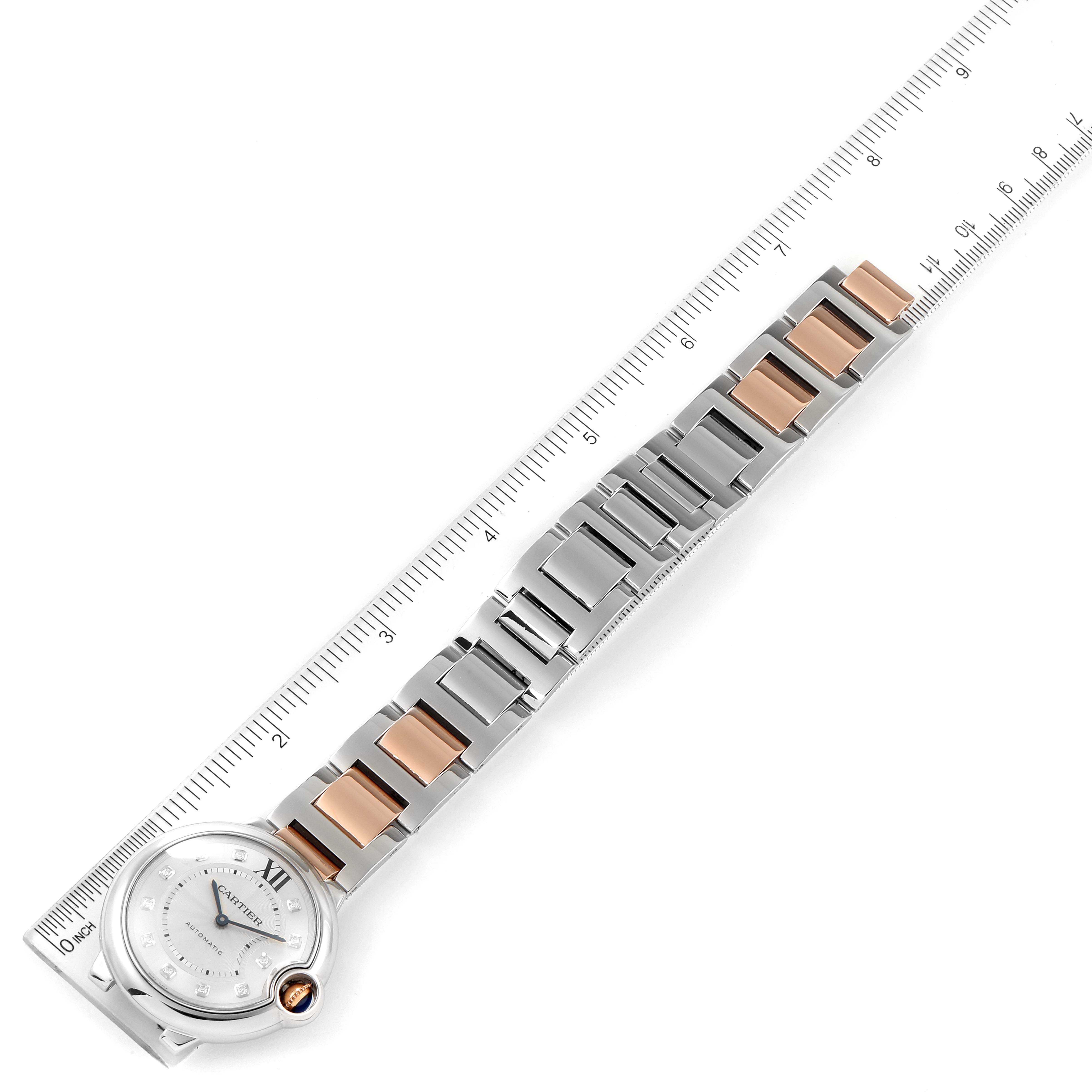 The image shows the Ballon Bleu model by Cartier from a top angle, highlighting the watch face and the metal bracelet with a ruler for scale.