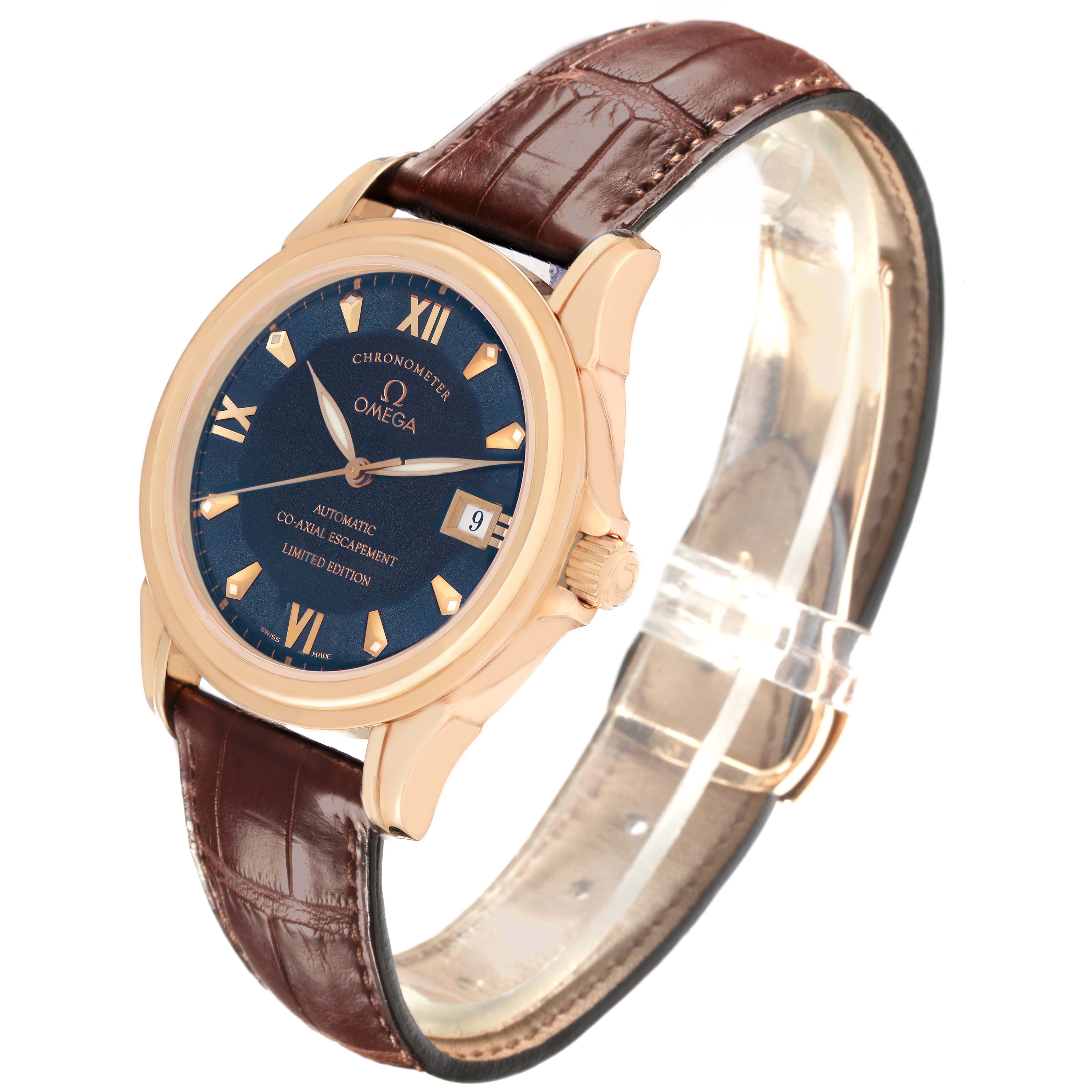 The Omega De Ville 5931.81.23 Men
s Rose Gold Blue Dial 5931.81.23 Men
s Rose Gold Blue Dial watch is shown at a tilted angle, displaying its blue dial, gold-tone case, crown, Roman numerals, and brown leather strap.