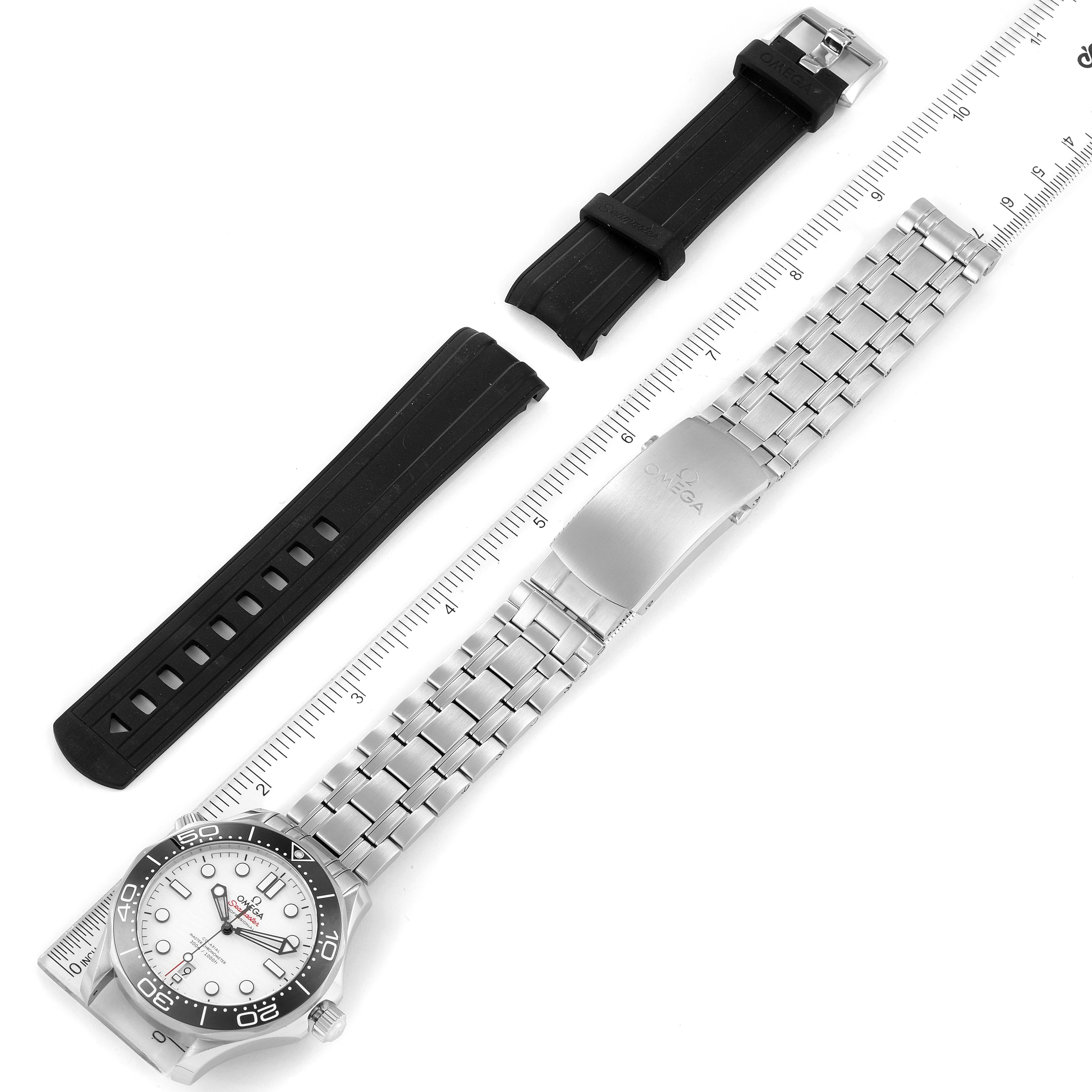 A top-down view shows the Omega Seamaster 210.32.42.20.04.001 Men's Stainless Steel White Dial 210.32.42.20.04.001 Men's Stainless Steel White Dial watch with its metal bracelet and an extra black rubber strap alongside a ruler.