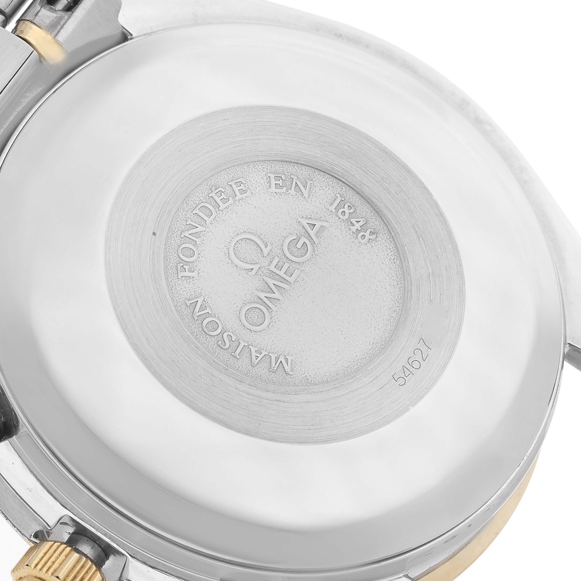 This image shows the back case of an Omega Speedmaster 3321.80.00 Men's Steel and Gold (two tone) Blue Dial 3321.80.00 Men's Steel and Gold (two tone) Blue Dial watch, highlighting the engraved details and part of the attachment.