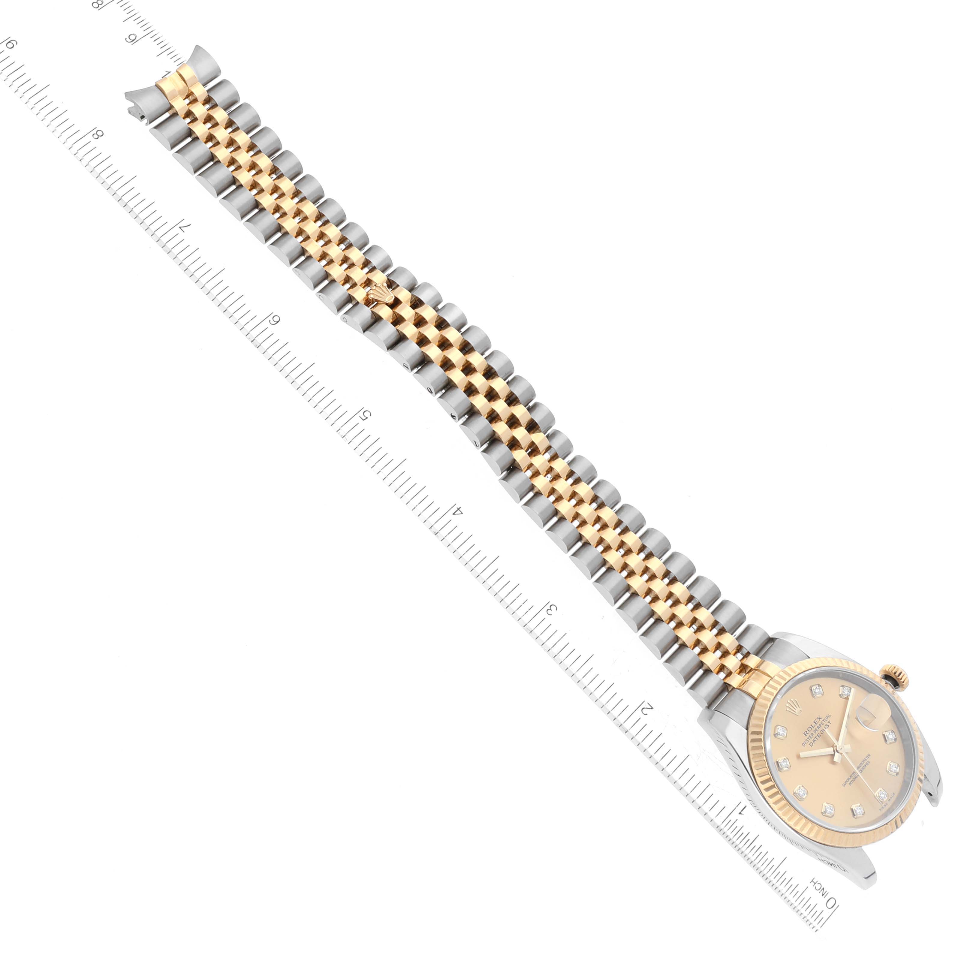 The image shows a Rolex Datejust 116233 Men's Steel and Gold (two tone) Champagne Dial 116233 Men's Steel and Gold (two tone) Champagne Dial watch from a top view, highlighting its face, dial, and two-toned metal bracelet alongside a ruler for scale.