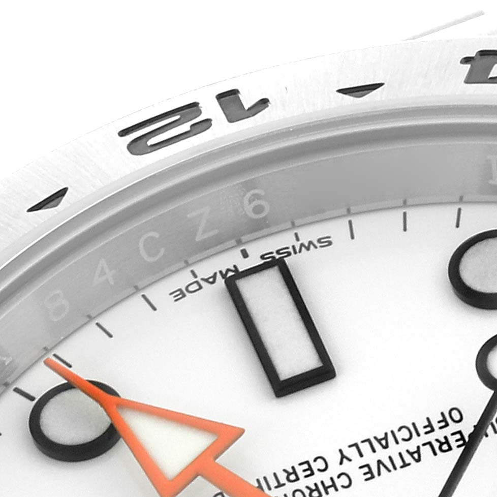 Close-up of the Rolex Explorer 216570 Men
s Stainless Steel White Dial 216570 Men
s Stainless Steel White Dial watch showing part of the dial, bezel with the number 12, and the orange GMT hand.