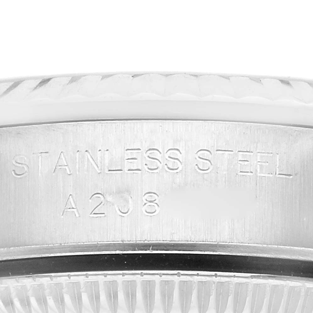 This close-up image of a Rolex Oyster Perpetual 76094 Women's Stainless Steel Blue Dial 76094 Women's Stainless Steel Blue Dial watch shows the engraved "STAINLESS STEEL" text and part of its fluted bezel.