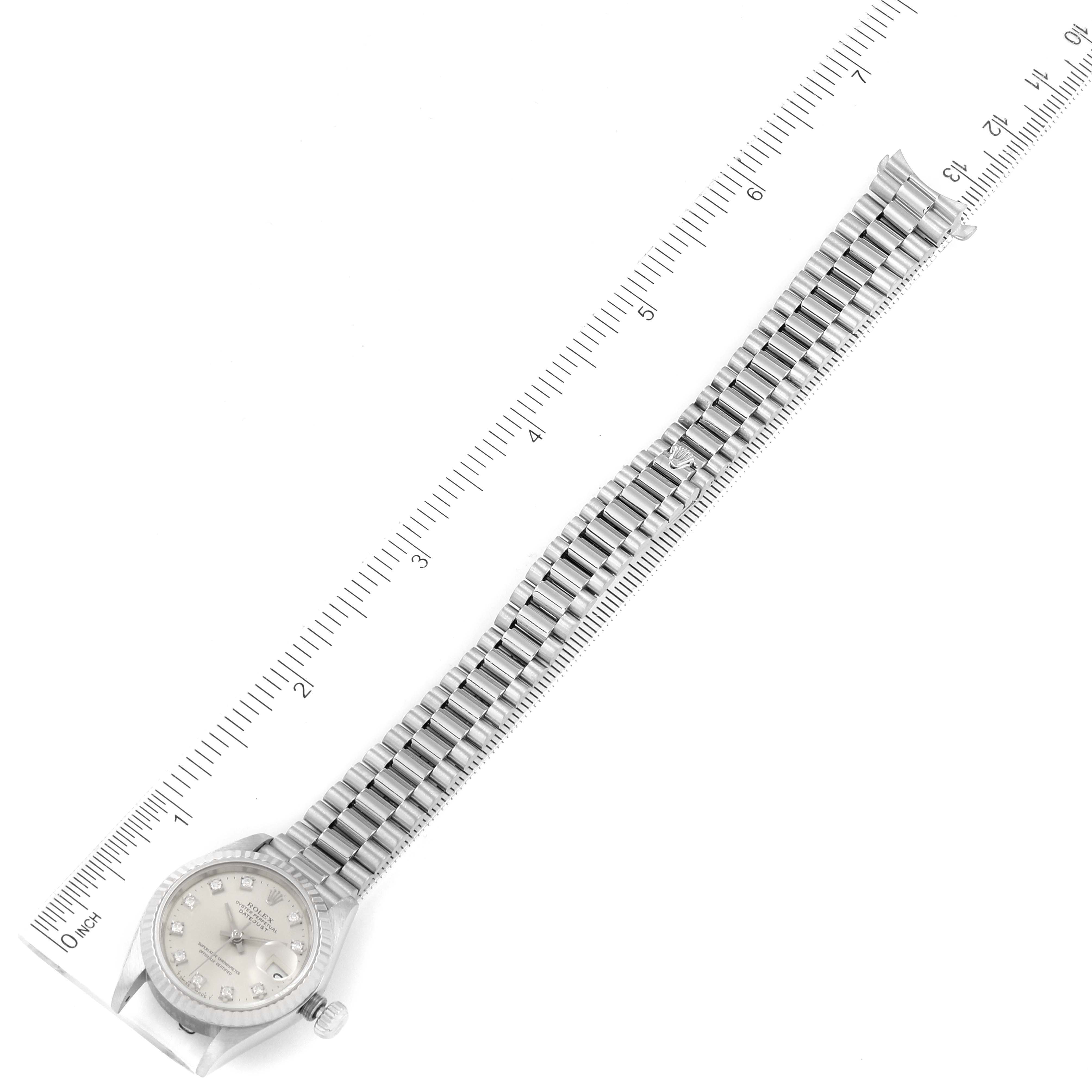 The image shows a top-down view of a Rolex President 69179 Women
s White Gold Silver Dial 69179 Women
s White Gold Silver Dial model watch, including the face, bracelet, and clasp, alongside a ruler for measurement.
