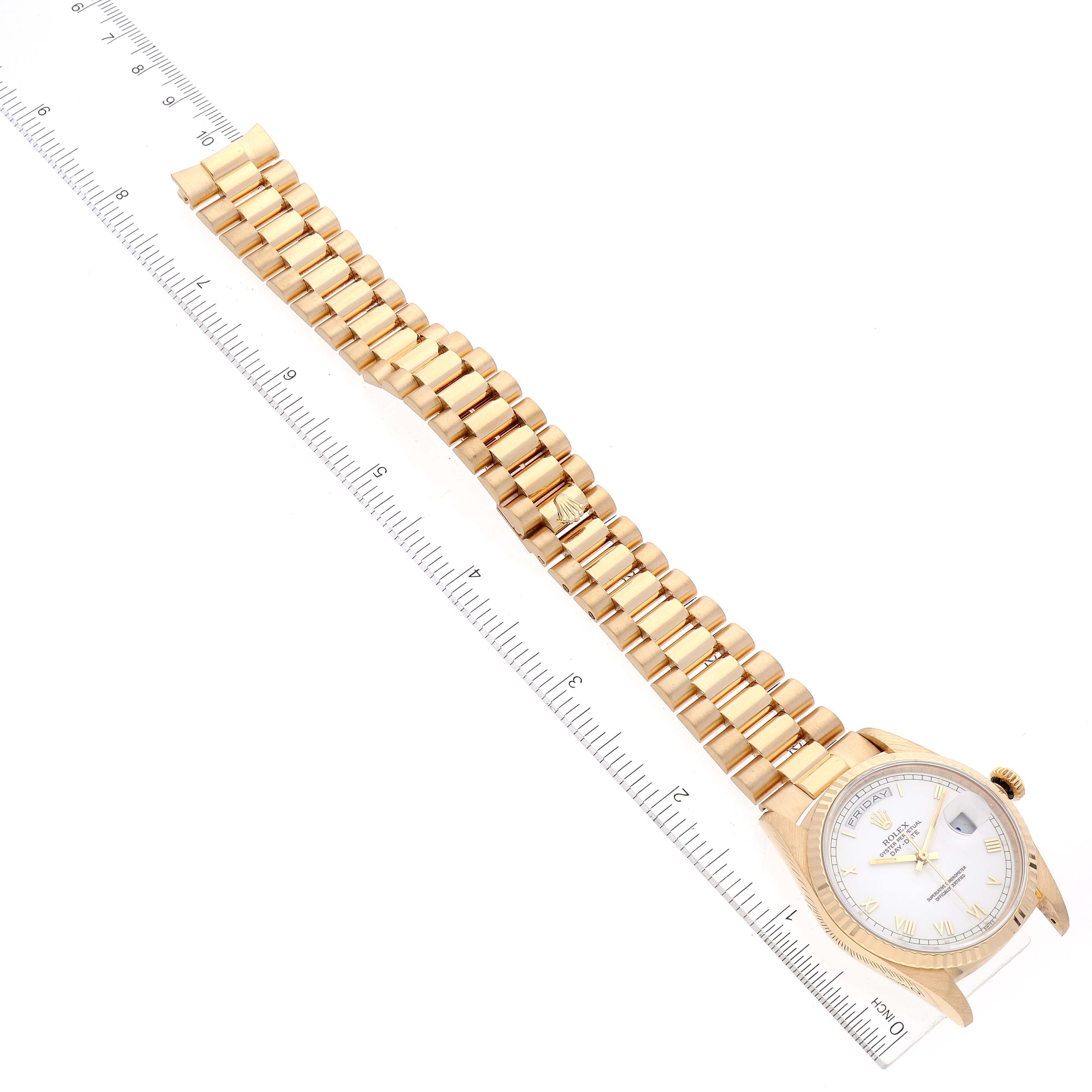 This image shows a Rolex President 18238 Men's Yellow Gold White Dial 18238 Men's Yellow Gold White Dial model watch in a top-down view, displaying its gold bracelet and face alongside a measuring ruler.