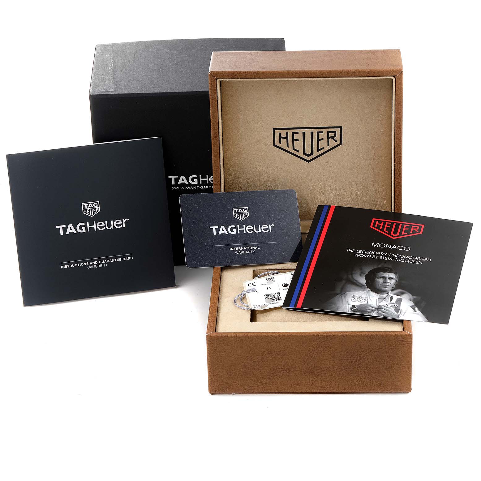The image shows the packaging, manuals, international warranty card, and accessories for the Tag Heuer Monaco CAW211P Men's Stainless Steel Blue Dial CAW211P Men's Stainless Steel Blue Dial model watch.