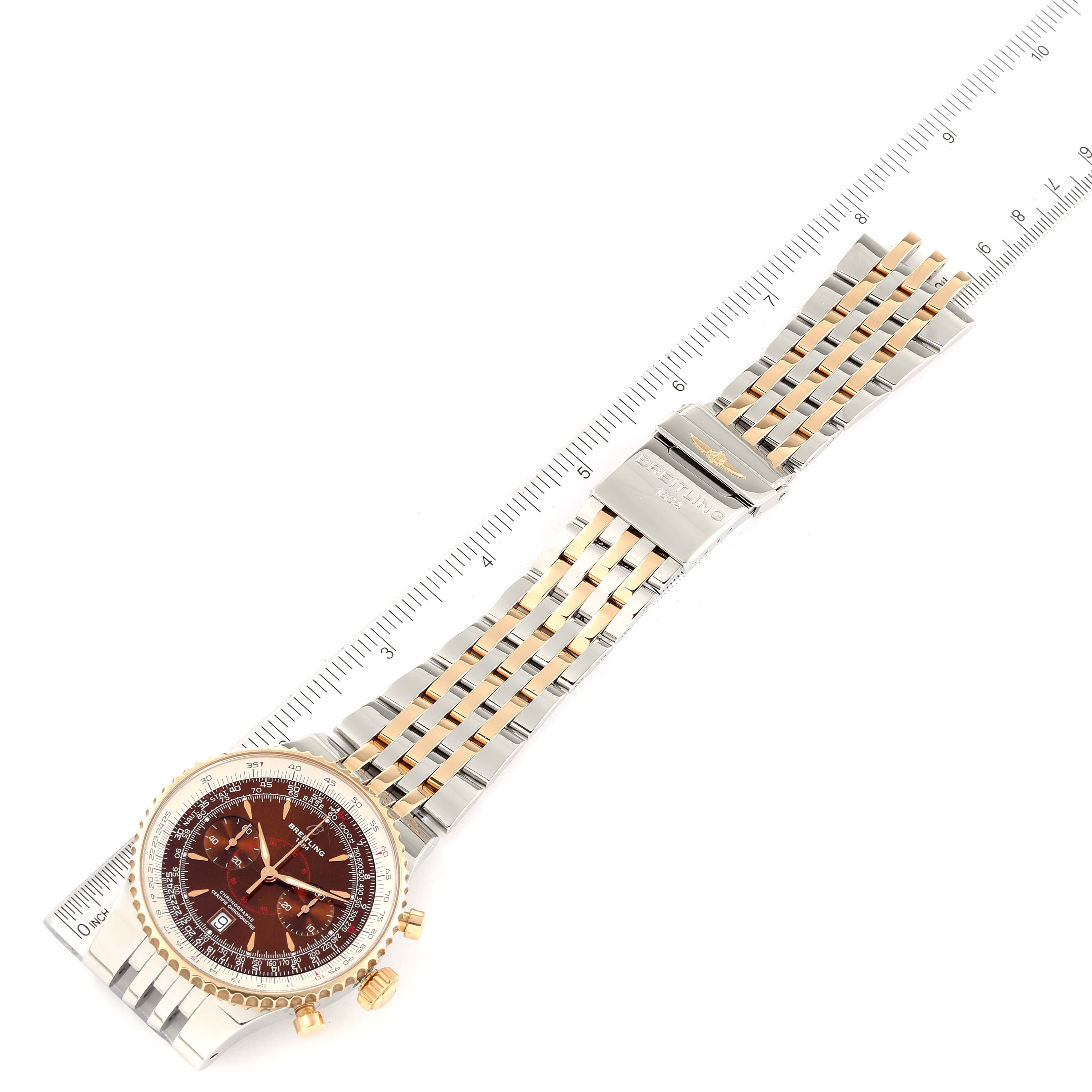 The Breitling Navitimer C23340 Men's Steel and Gold (two tone) Brown Dial C23340 Men's Steel and Gold (two tone) Brown Dial watch is shown face-up with an attached ruler for size reference, displaying its dial, bezel, and bracelet.
