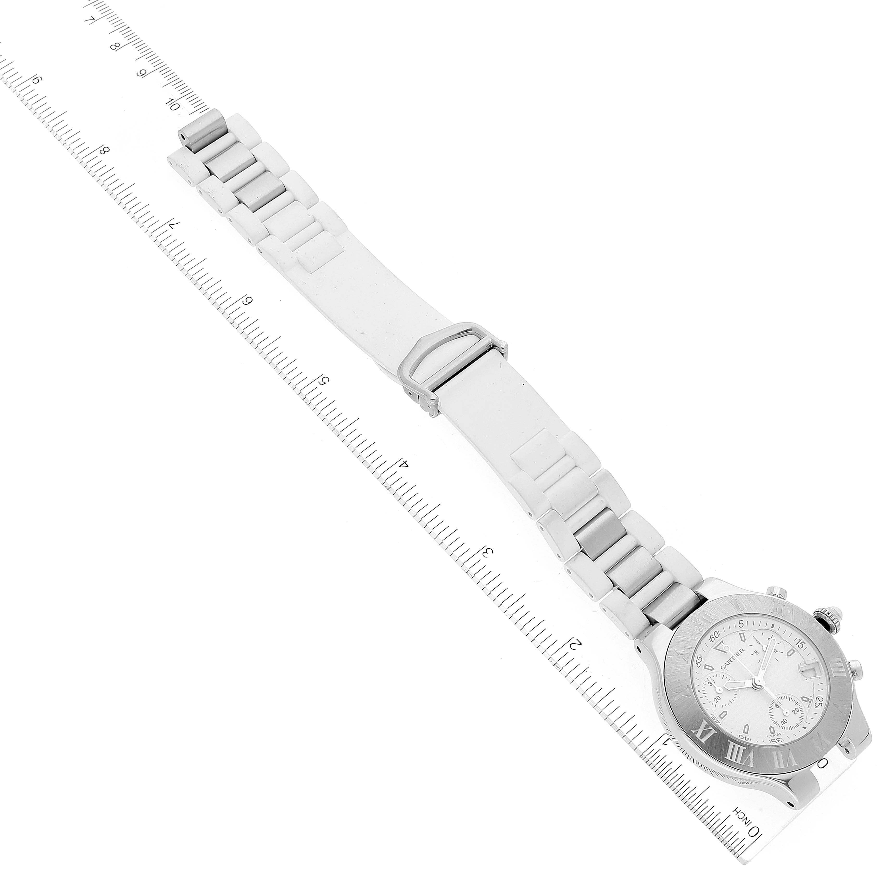 The image shows an aerial view of a Cartier Must 21 W10184U2 Women's Stainless Steel White Dial W10184U2 Women's Stainless Steel White Dial watch and its bracelet, aligned with a ruler for scale.